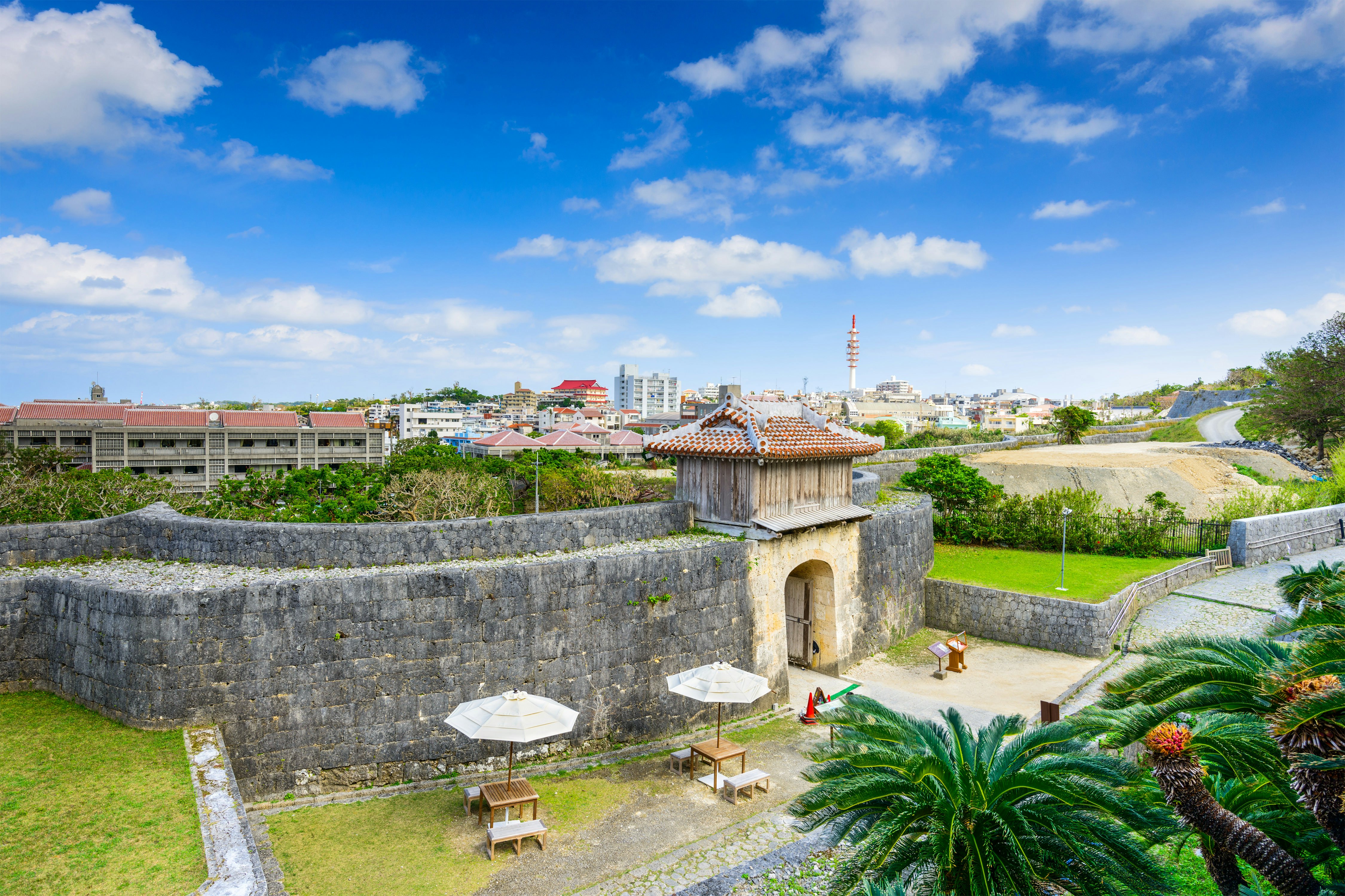 A solid stone castle wall and gateway on the edge of a city.