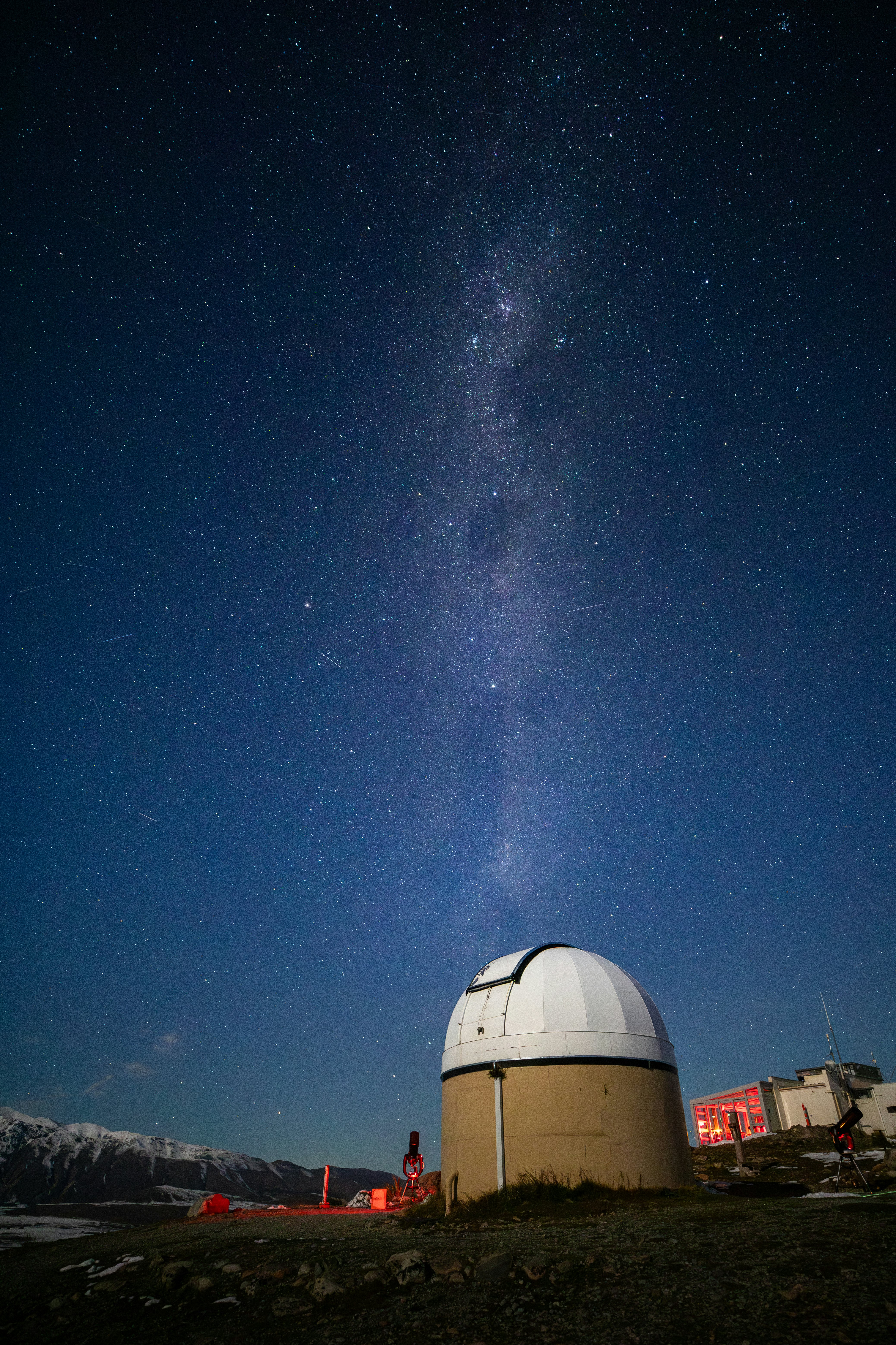 A telescope and an observatory under a starry night sky.