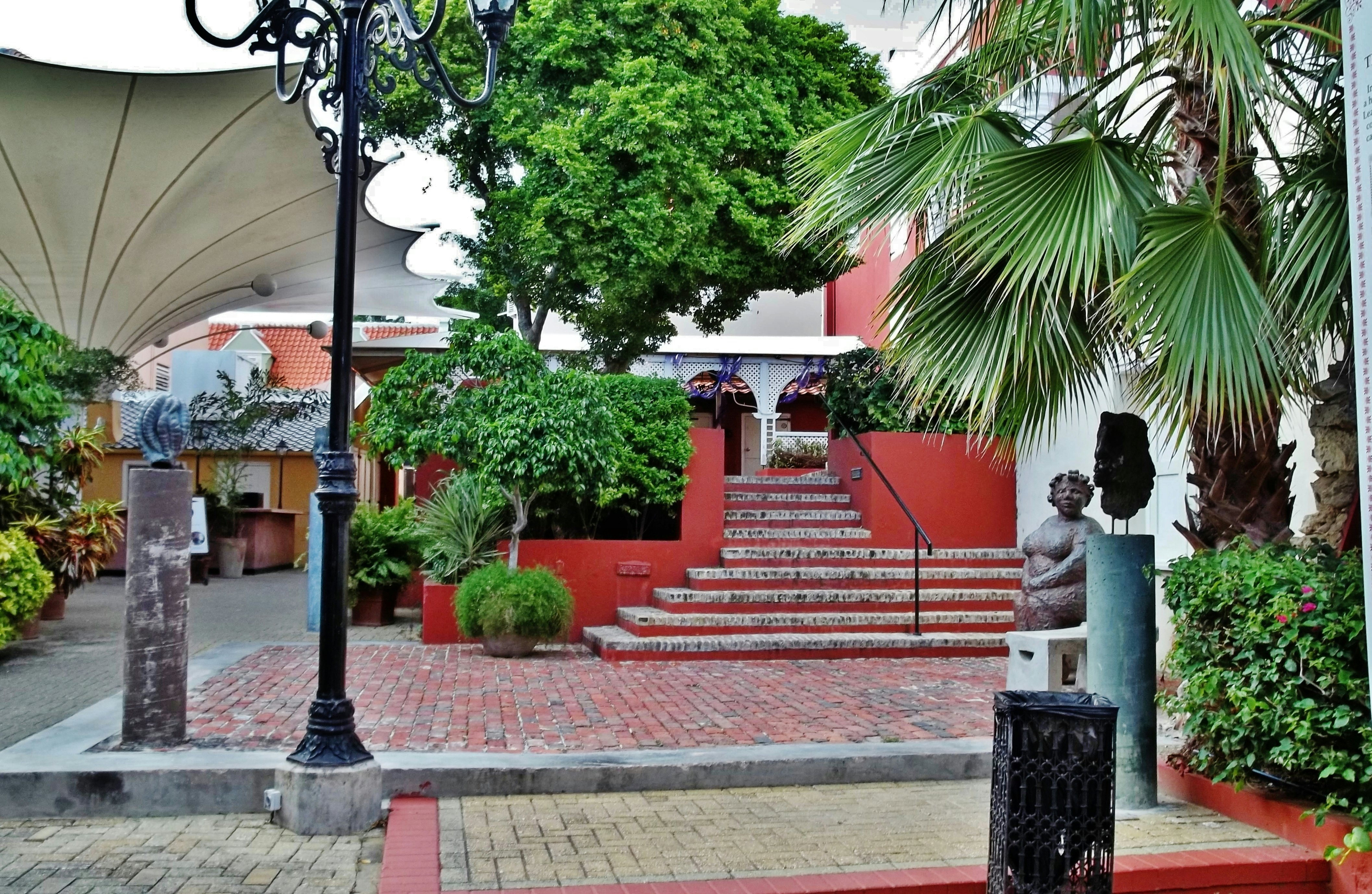 Entrance to the Kura Hulanda Museum with trees and sculptures