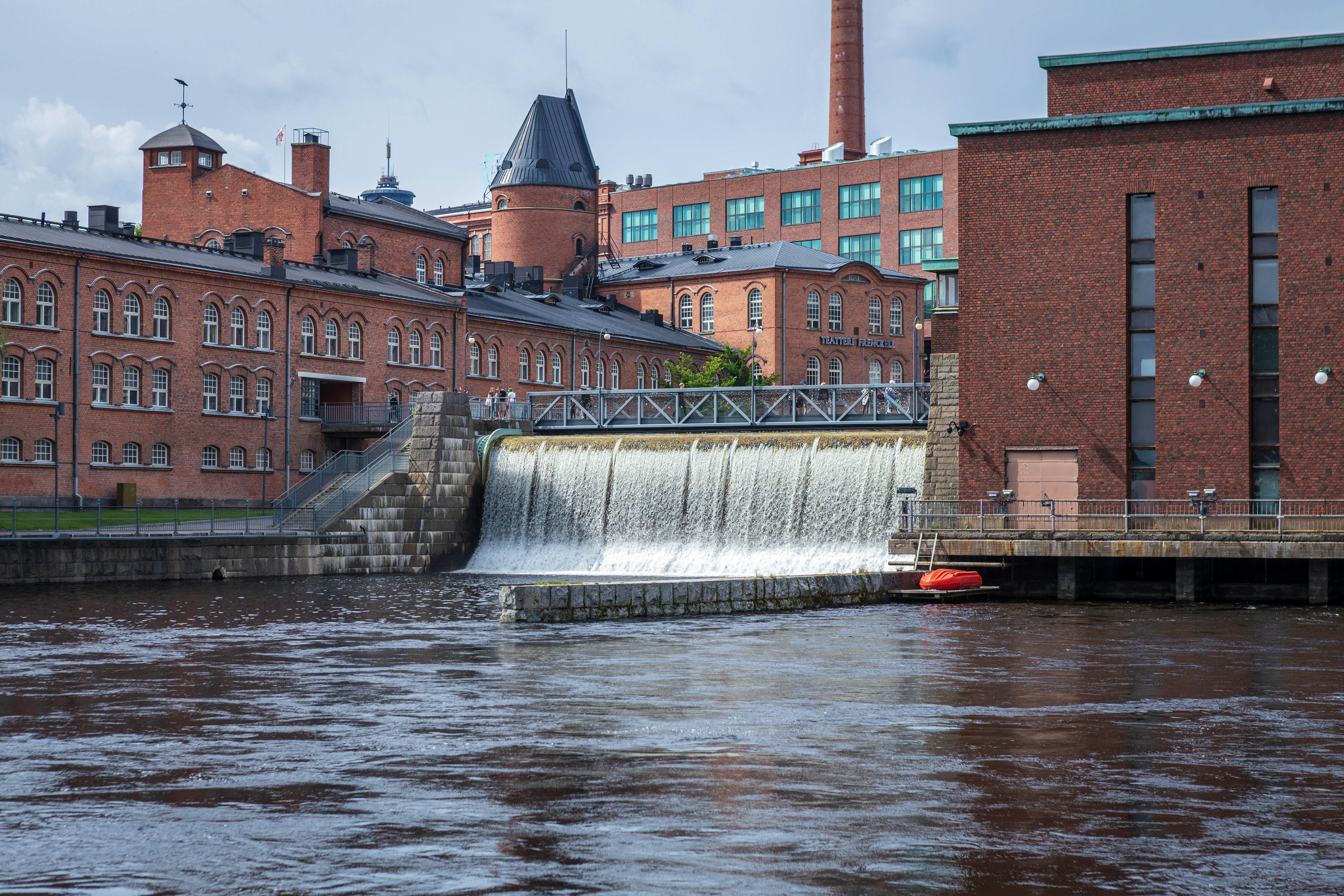 Water rushes through a sluice by red brick buildings in Finland.
