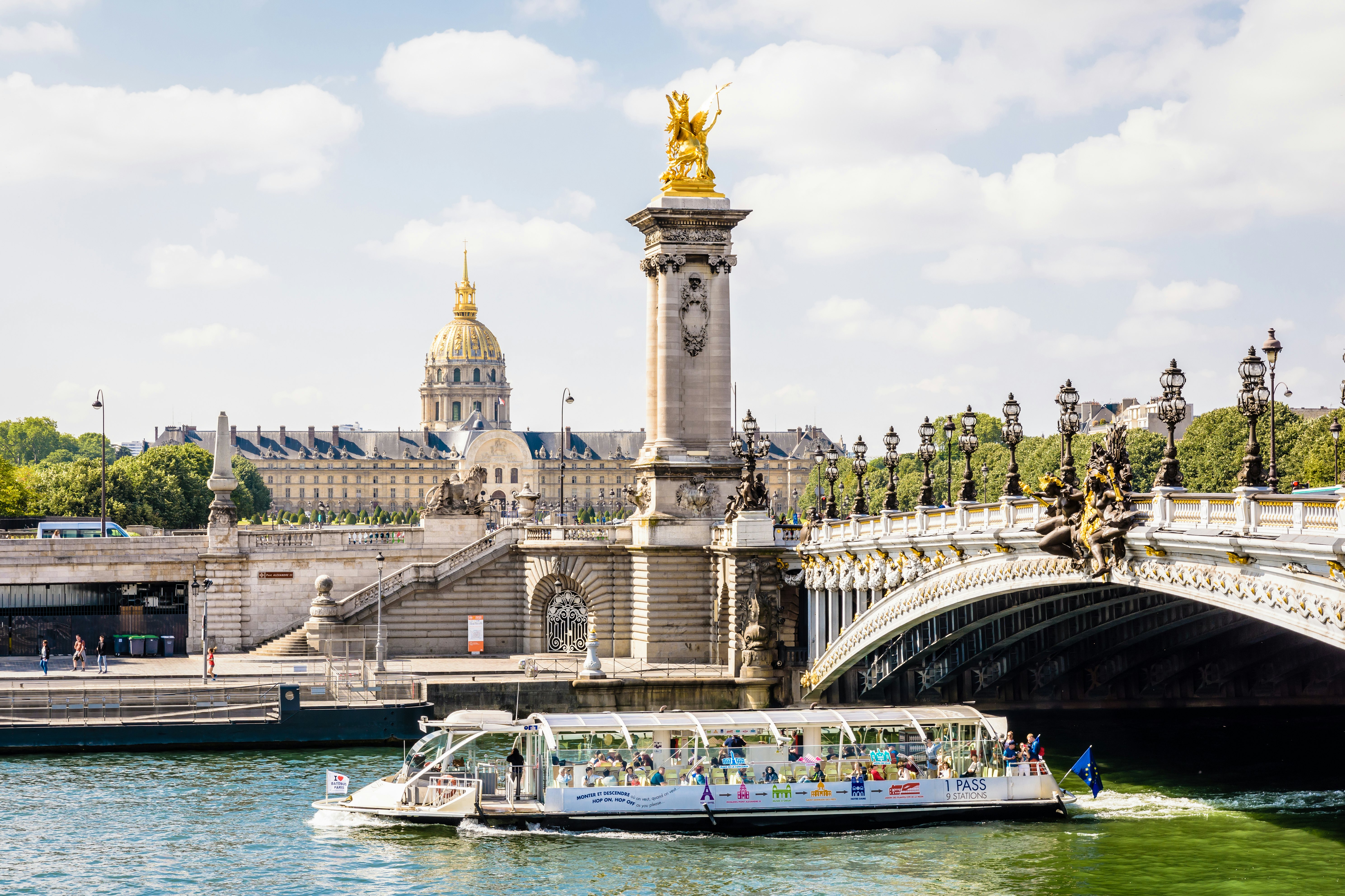 A Batobus shuttle riverboat full of tourists passes under the Pont Alexandre III.