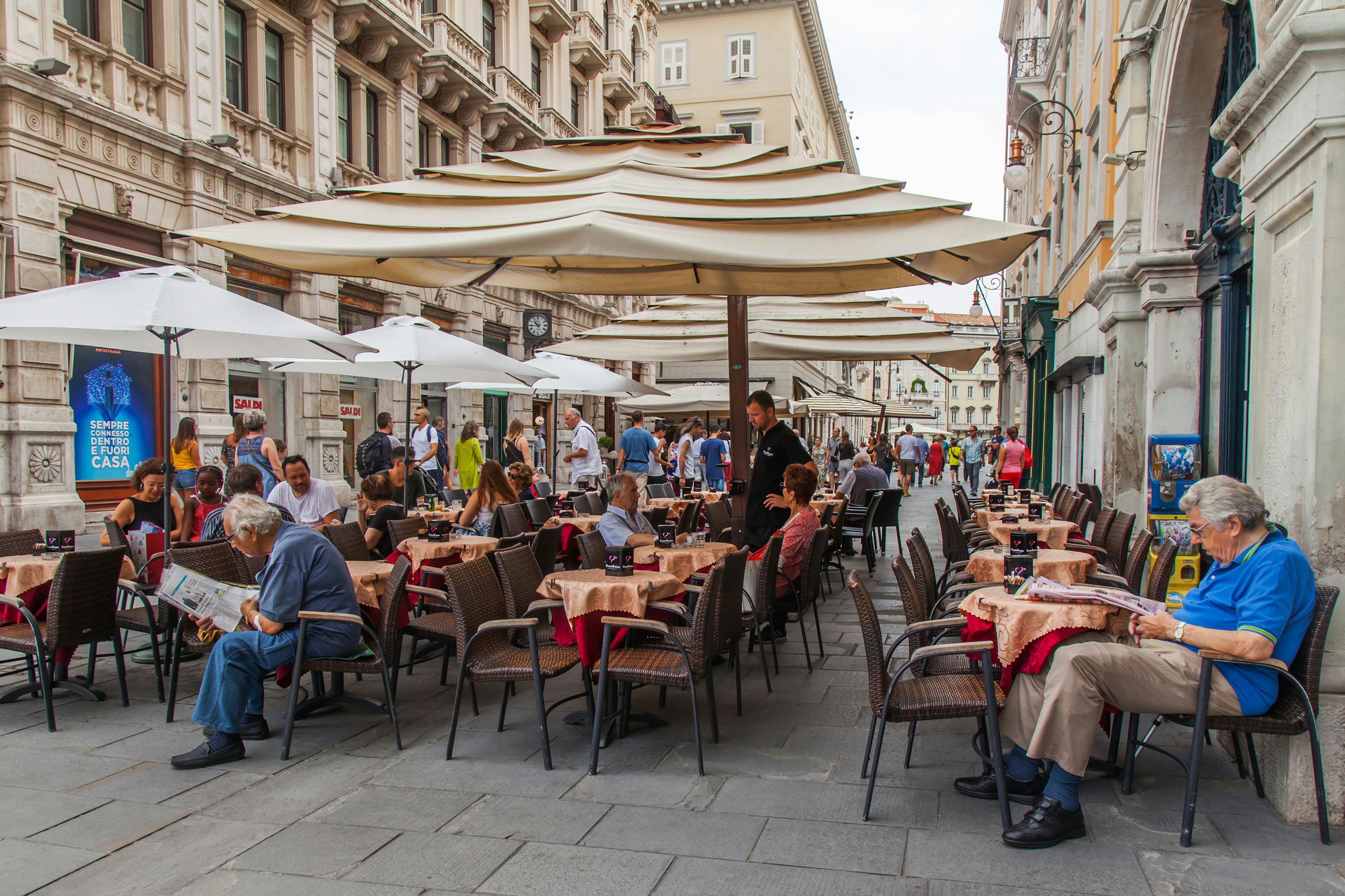 Attractive cafe tables on the sidewalk of a picturesque street in the historic city of Trieste, Italy.