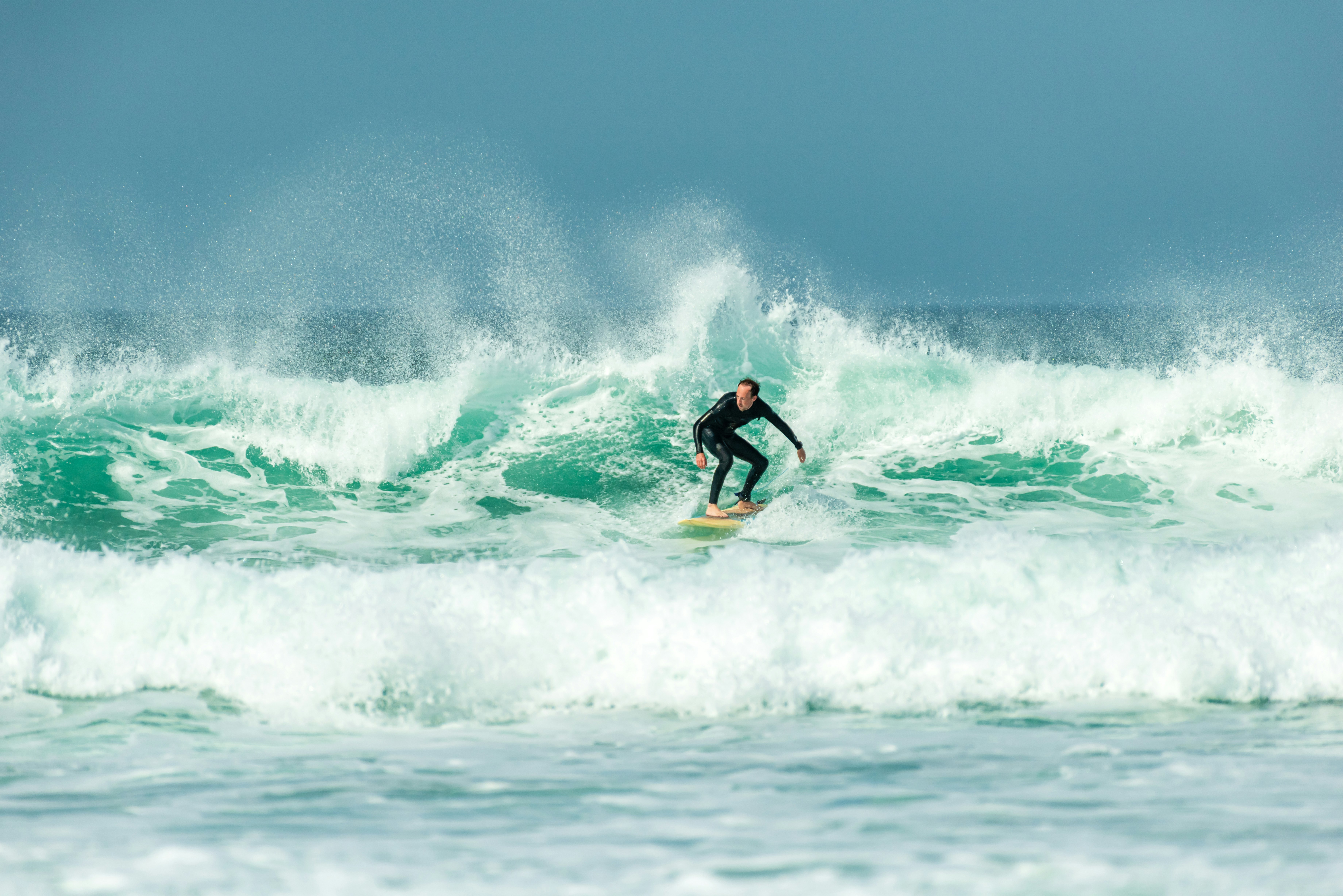 A surfer on big waves at Fistral Beach, Newquay, Cornwall, UK.
