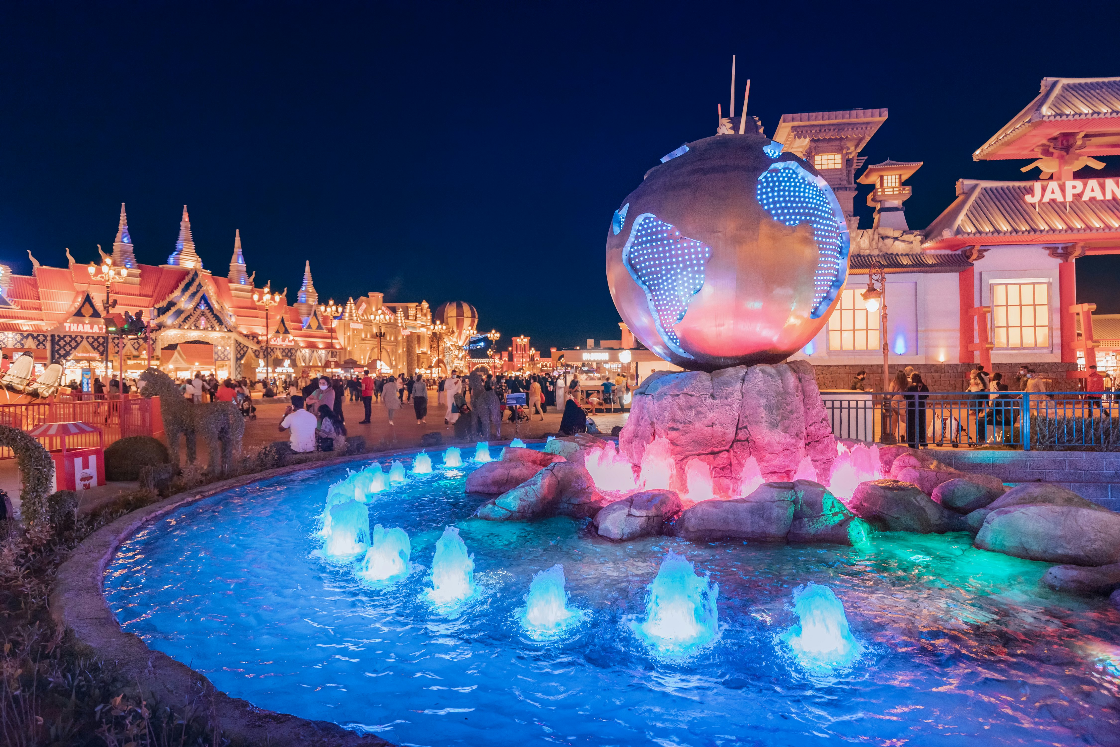 Illuminated fountain and water channel with a bronze globe on the square in Global Village