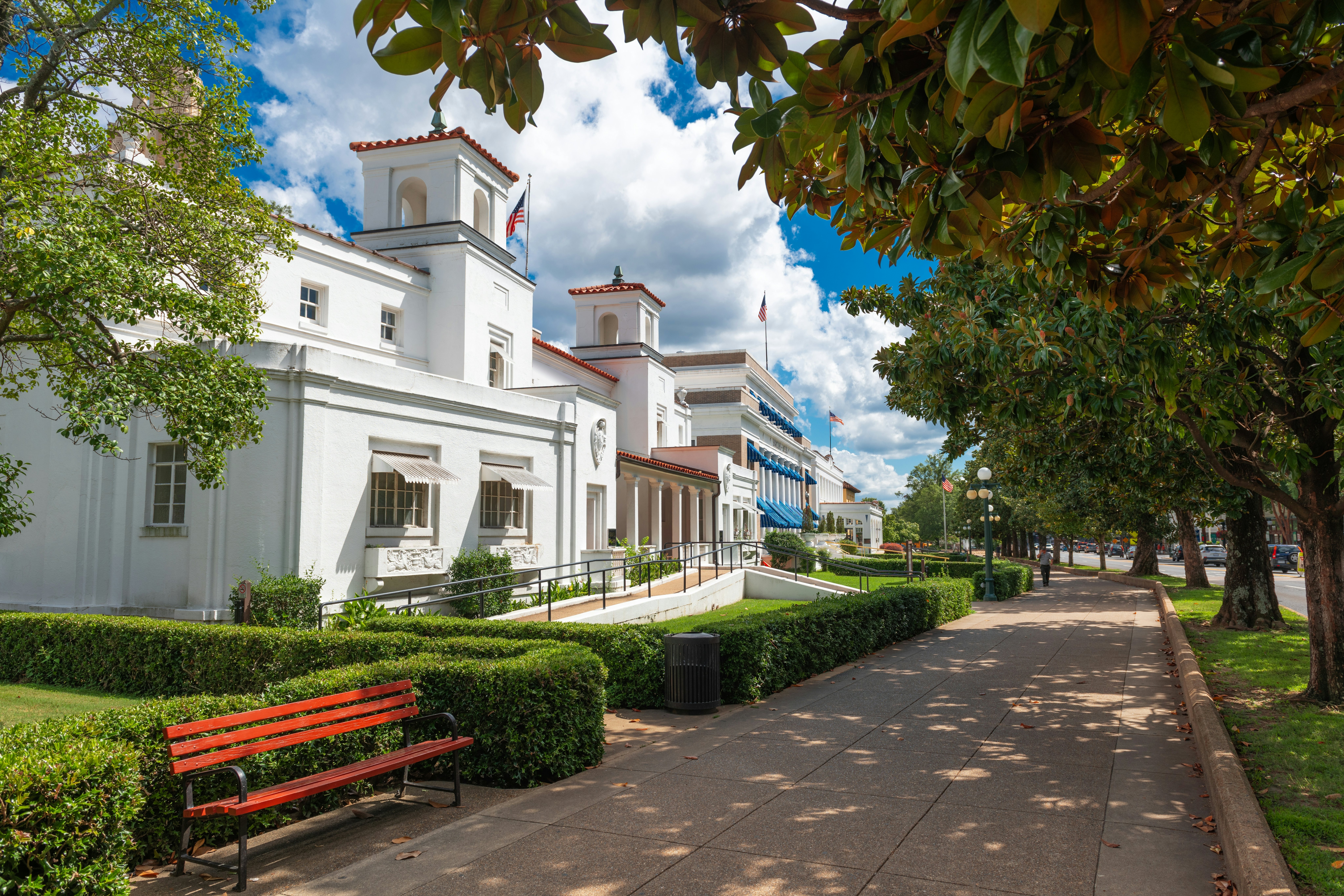 Grand hotels and spa buildings line a leafy street in a town.