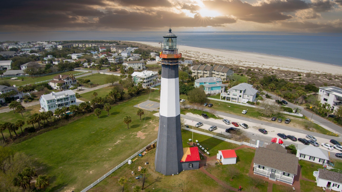 aerial shot of the a gorgeous spring landscape at Tybee Island Beach with the lighthouse, blue ocean water, a brown sandy beach, homes and lush green trees and grass in Tybee Island Georgia USA License Type: media Download Time: 2024-06-17T11:41:53.000Z User: clairenaylor Is Editorial: No purchase_order: