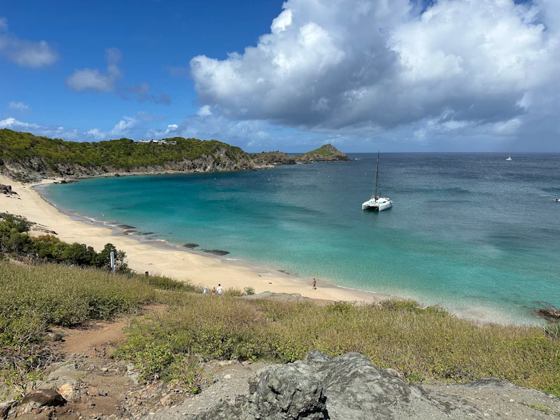 A sparse beach with one boat floating in its waters