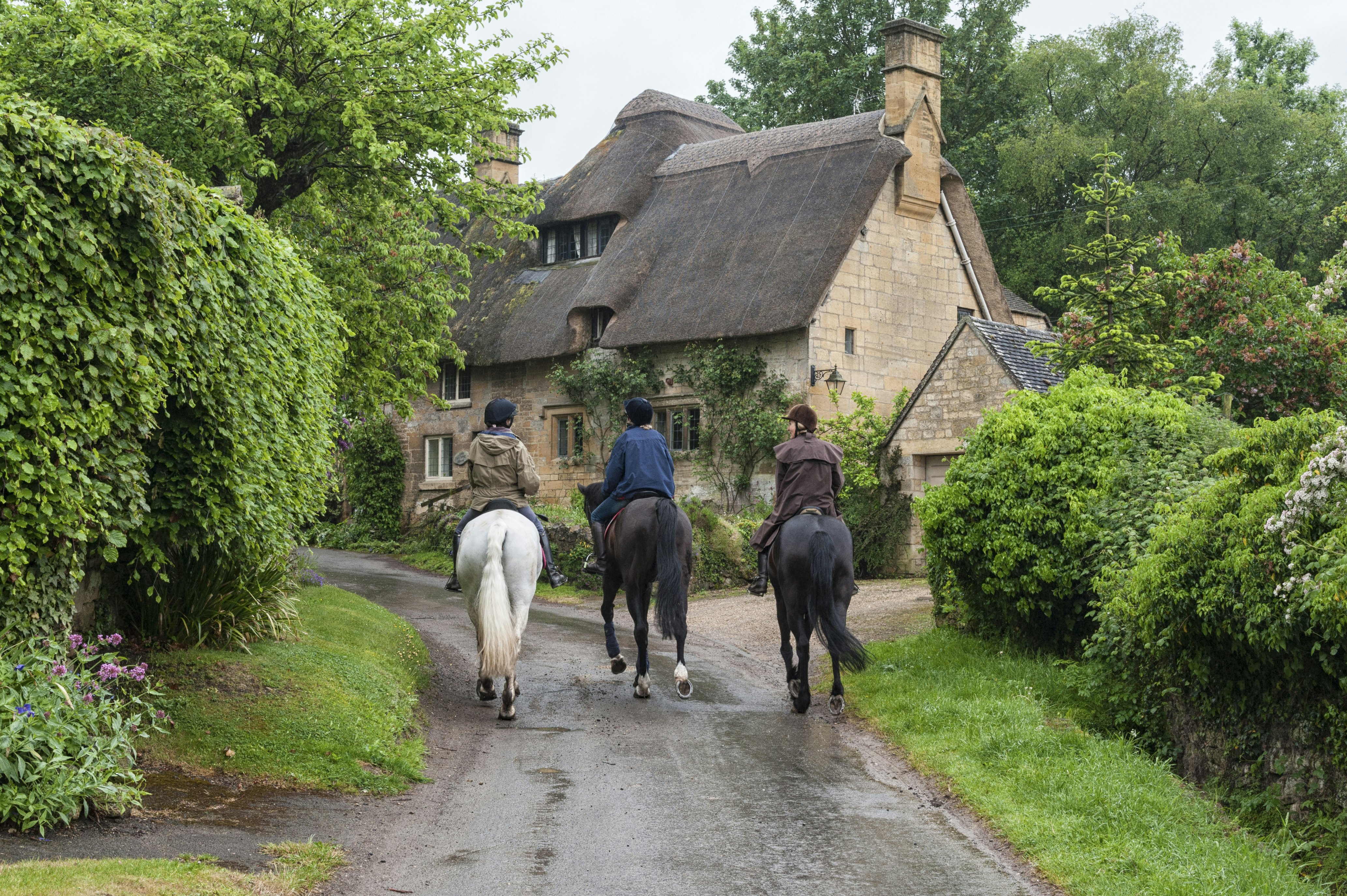 Unidentifed people and horses near cottages in the village of Stanton, Cotswolds district of Gloucestershire.