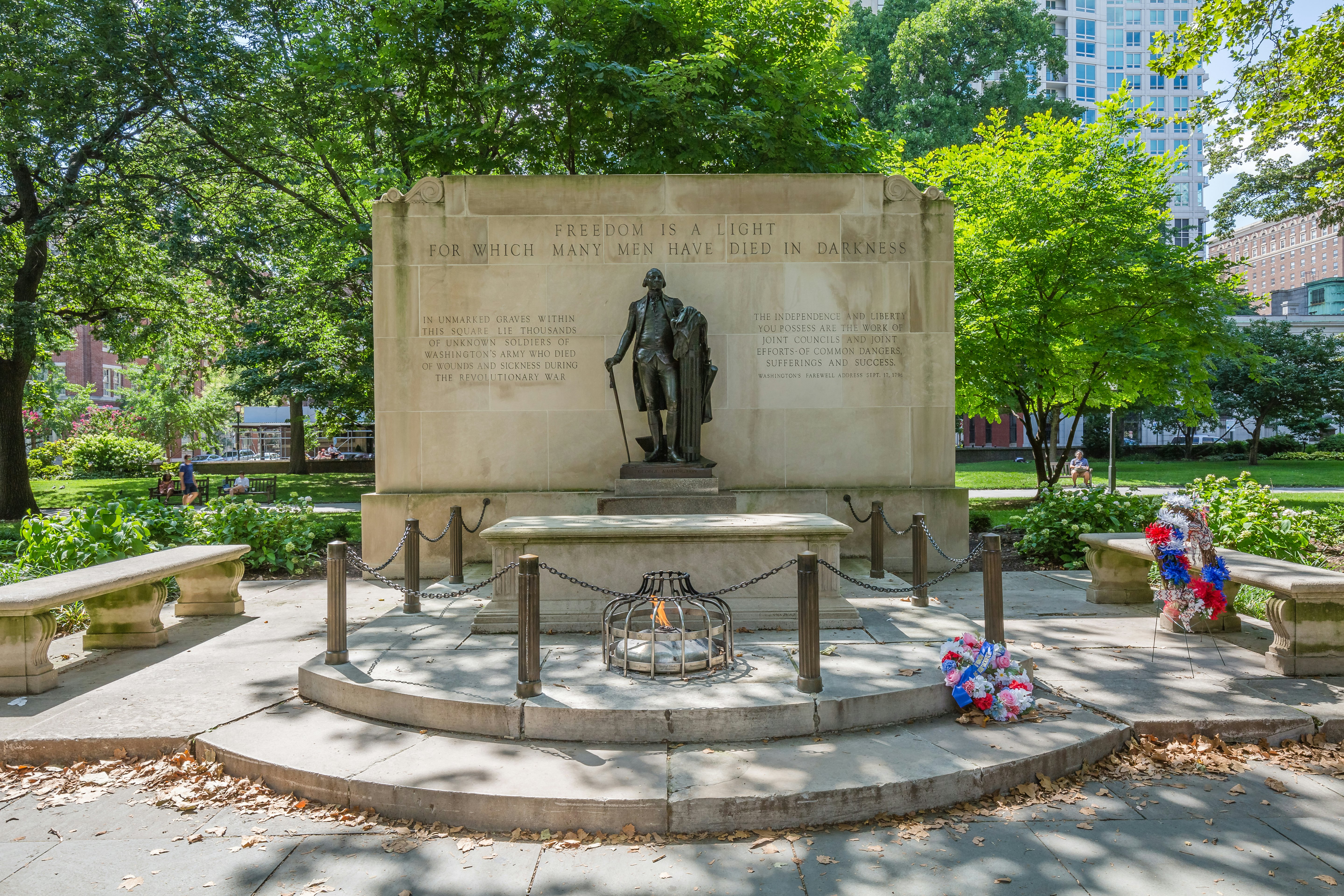A large memorial tombstone with stone benches flanking both sides