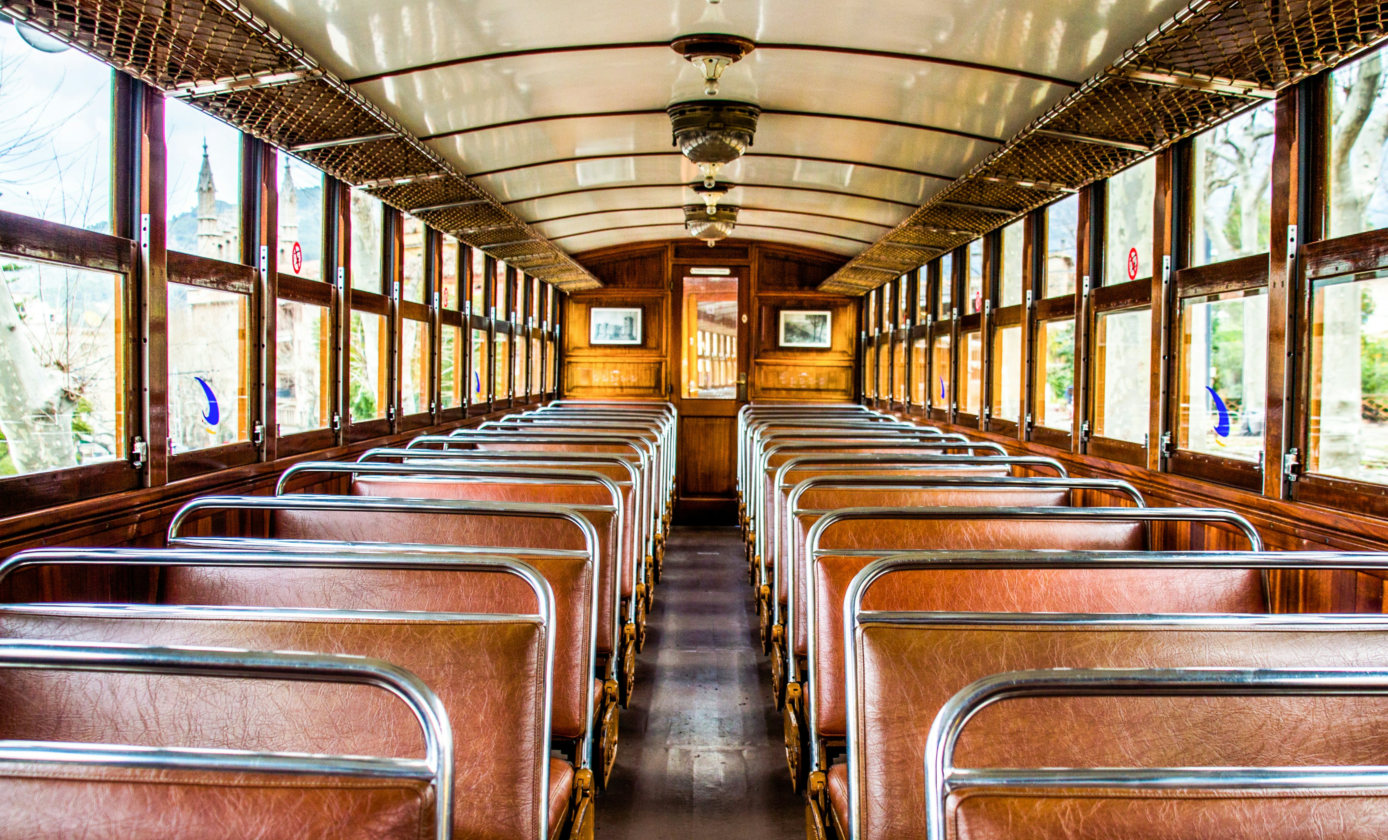 An empty wooden train coach with brown leather seats.