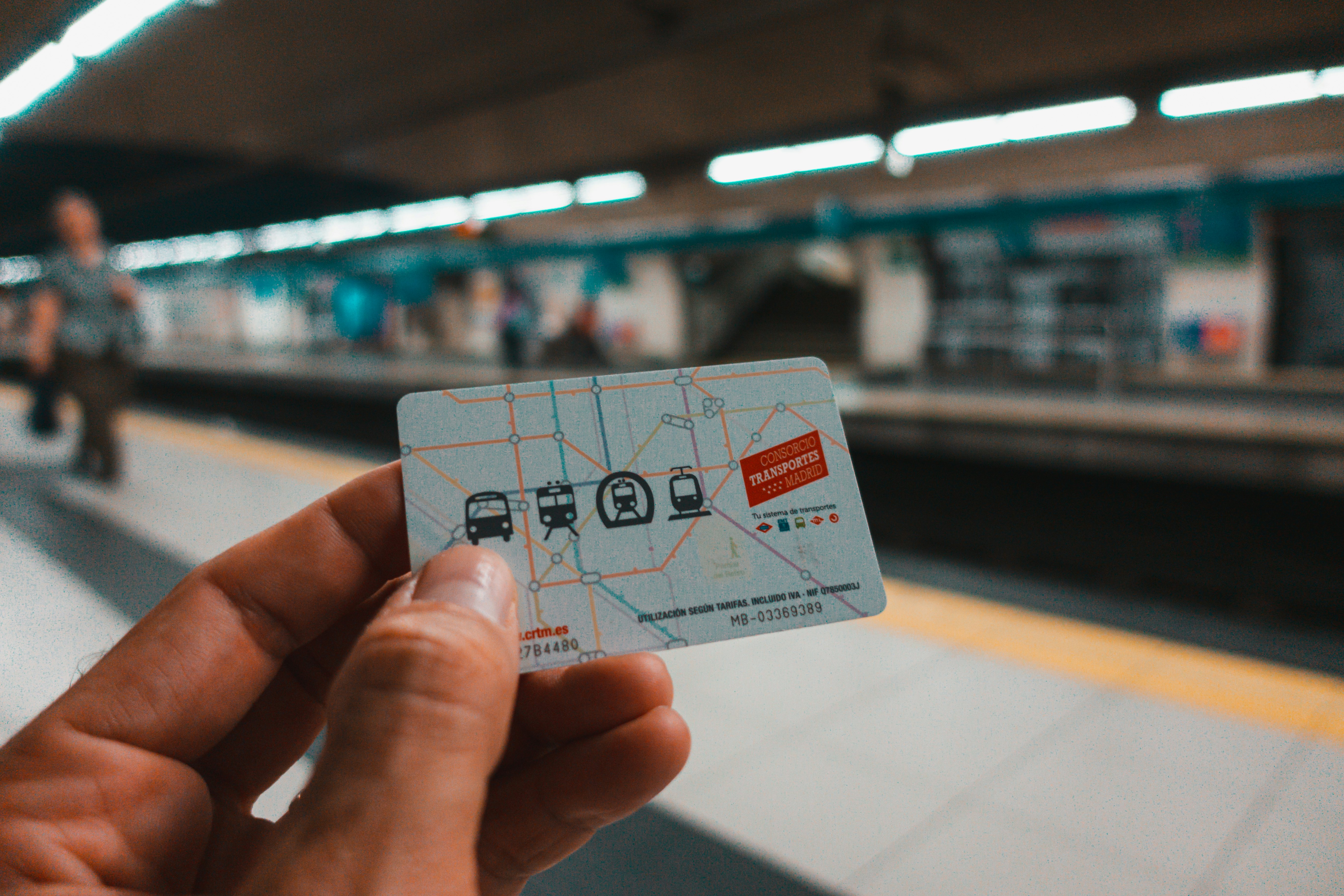 A hand holding a transit card for Madrid, showing four icons of the transit types.