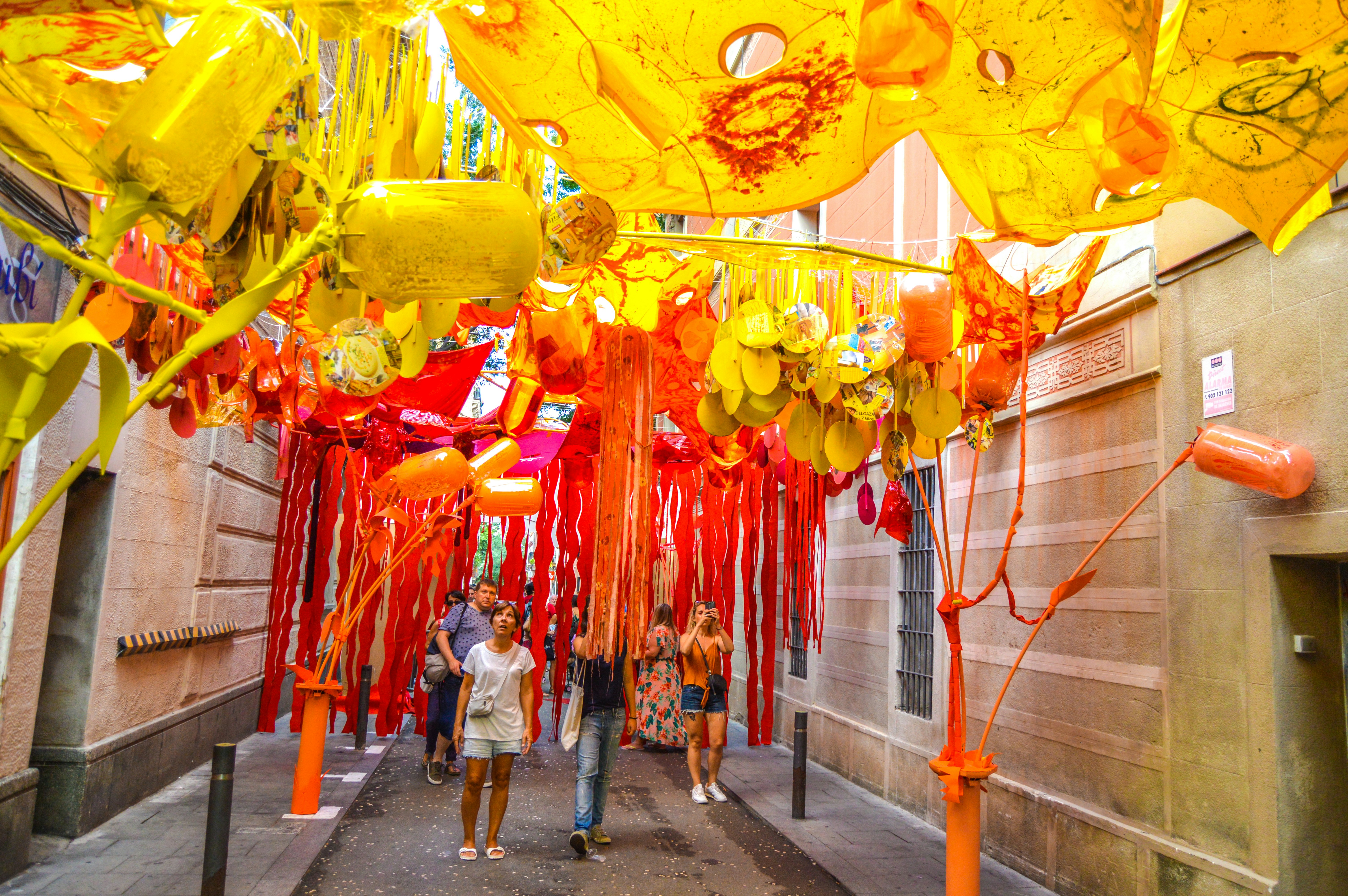 People wander down a street that has been decorated with balloons and streamers fashioned to look like flowers and plants.