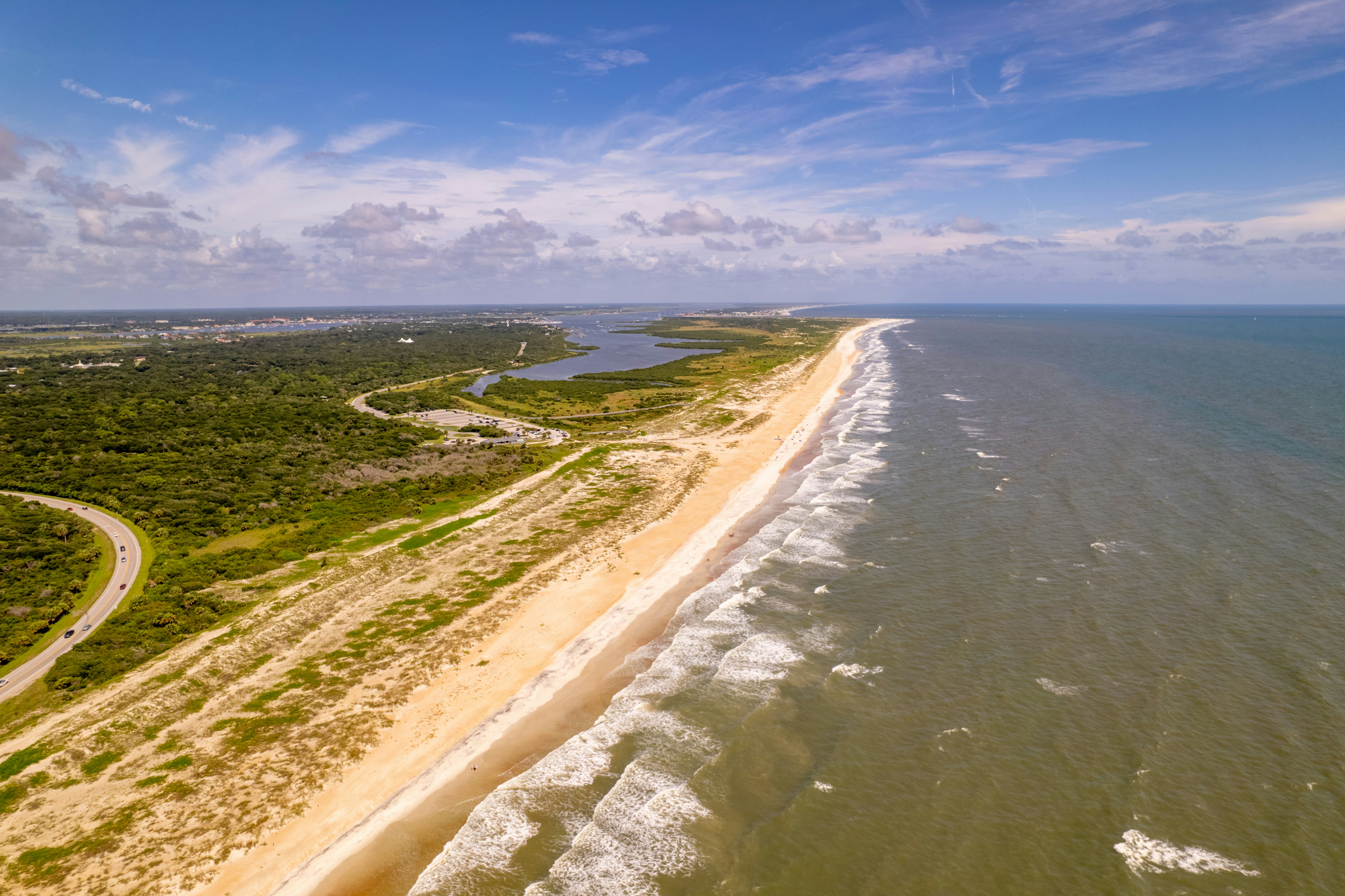 A sandy beach stretches into the distance. It's backed by dunes and woodland.
