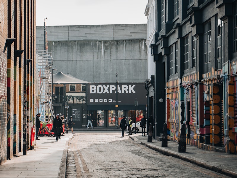 View of Boxpark Shoreditch, a shipping container mall for independent fashion and lifestyle stores and cafes, from a nearby street, selective focus on the background.