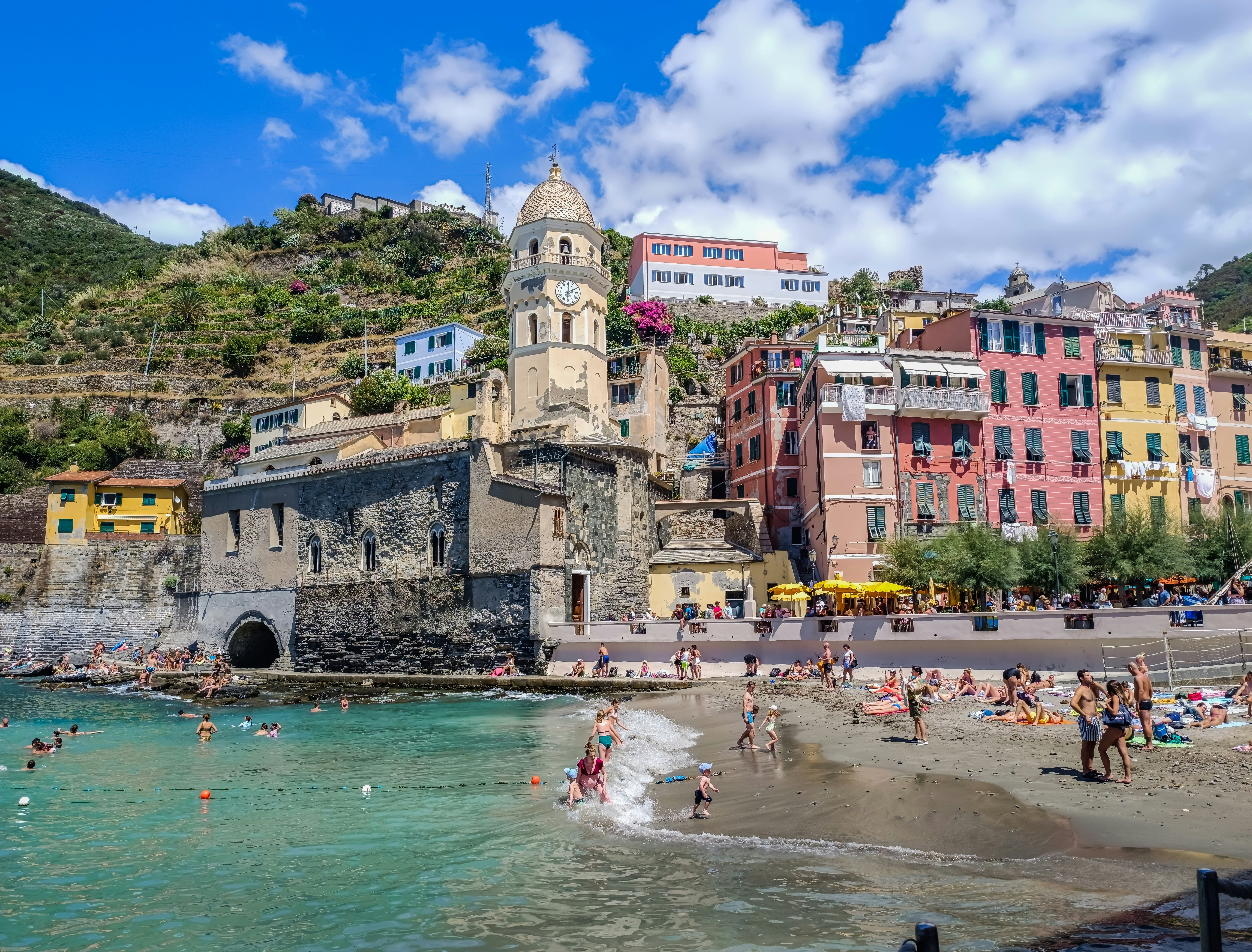 Families on the beach in front of the Santa Margherita di Antiochia church, Vernazza in the Cinque Terre, Italy
