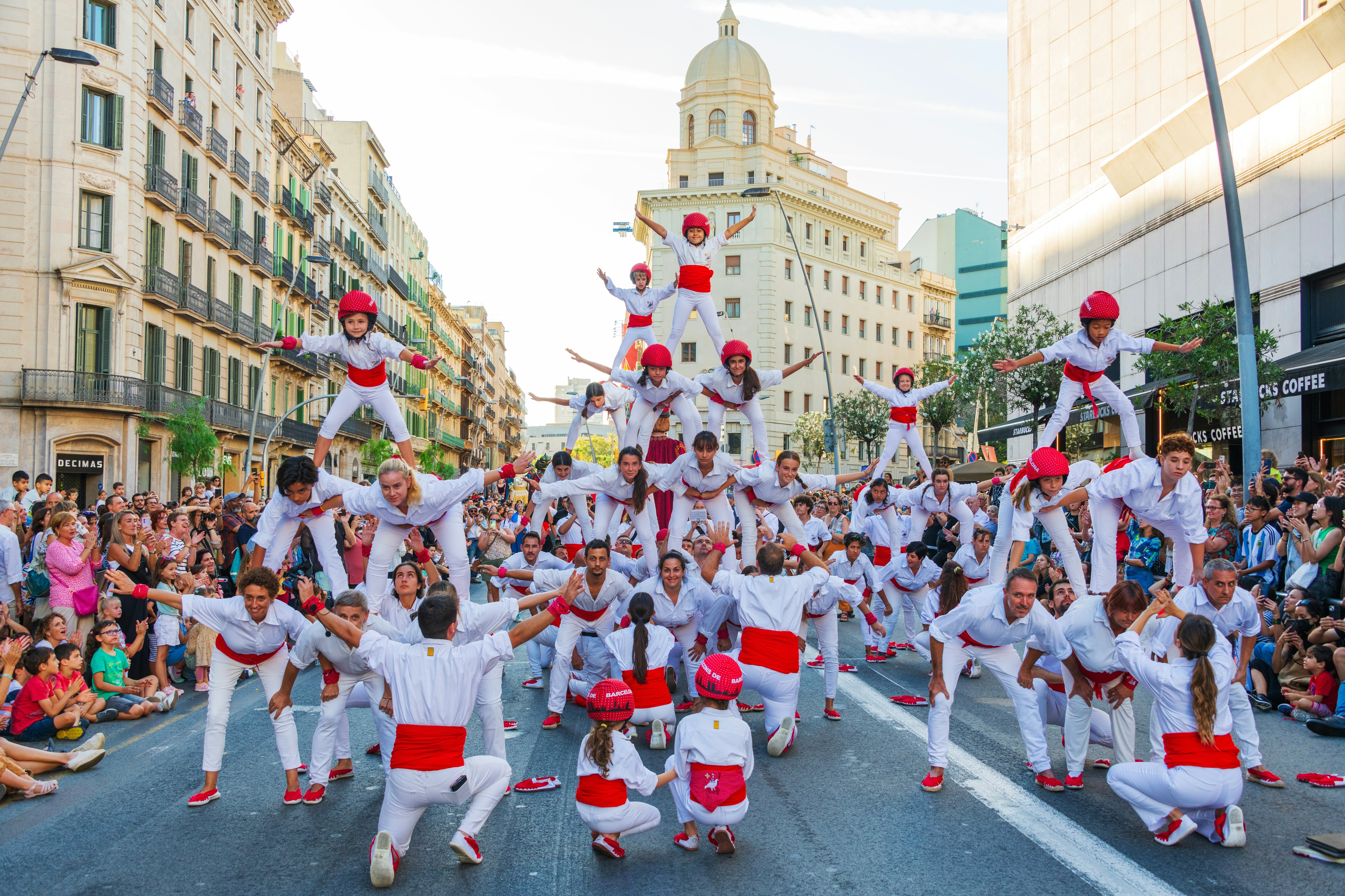 Performers wearing white and red make a human pyramid at a street festival in Barcelona.