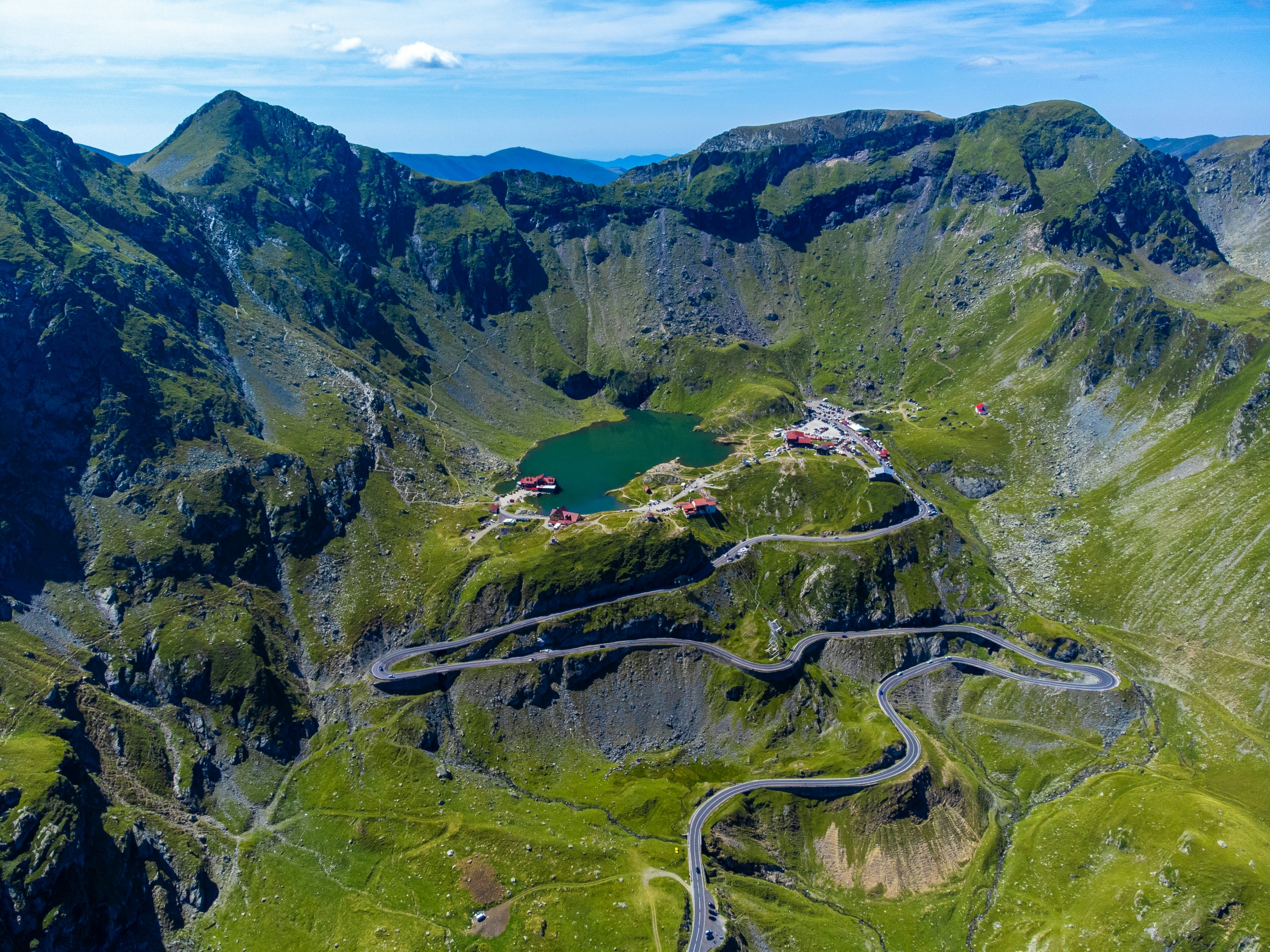 Hairpin turns on a road across a mountain that leads to a lake.