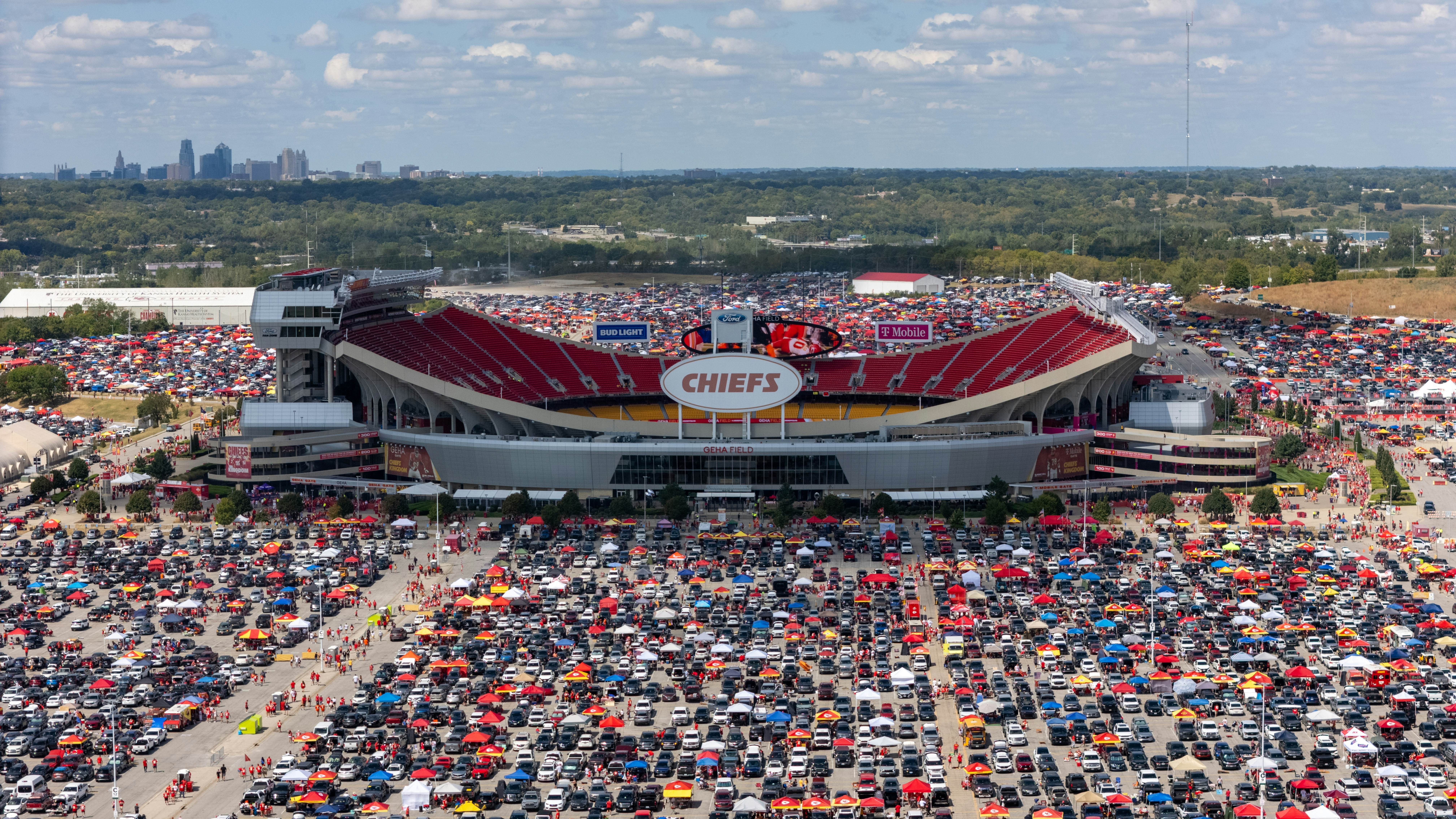 A vast stadium surrounded by parked cars on match day.