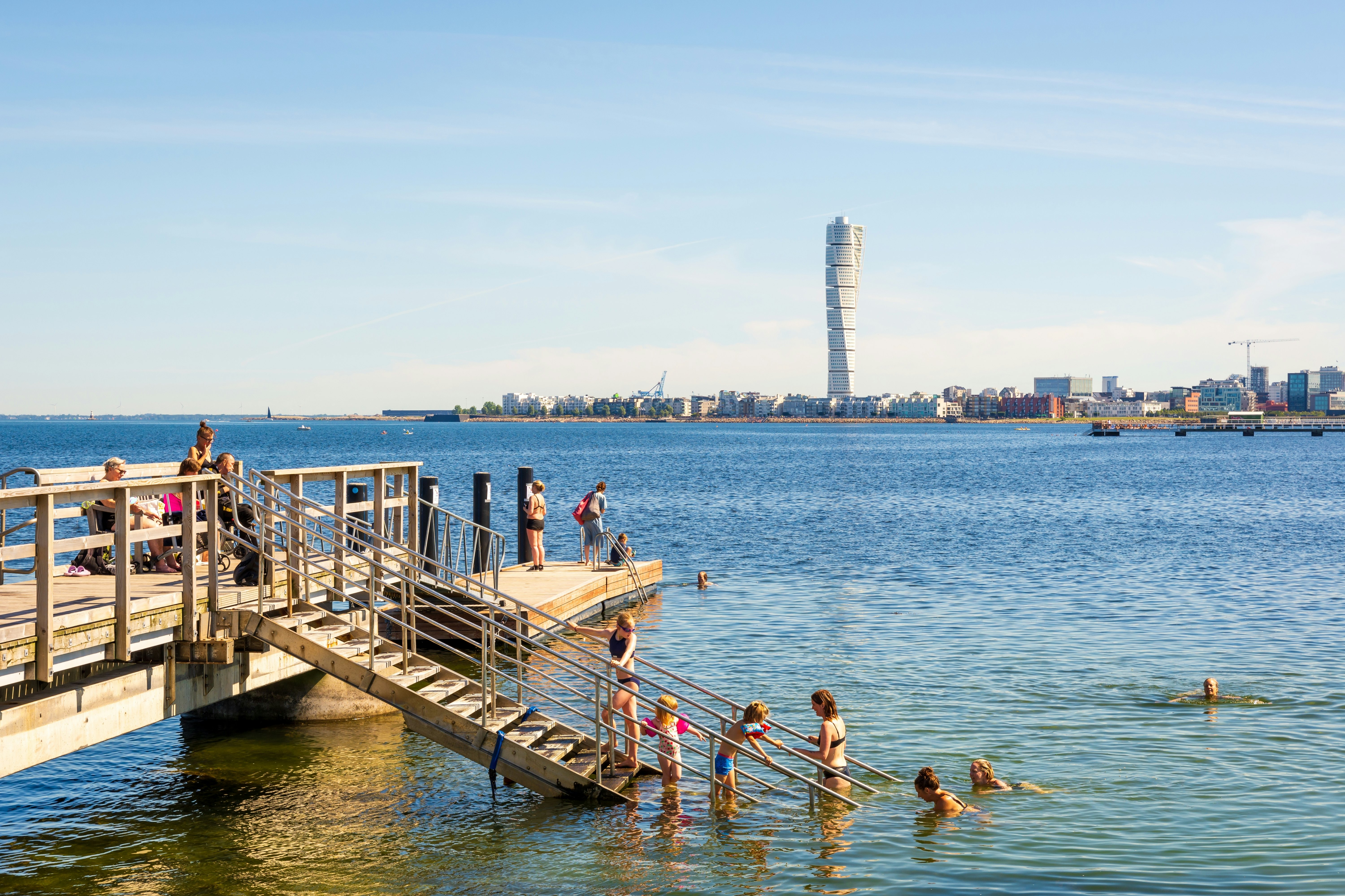 Families enjoying sea bathing on a sunny summer day on a pier at Ribersborg beach in Malmö.
