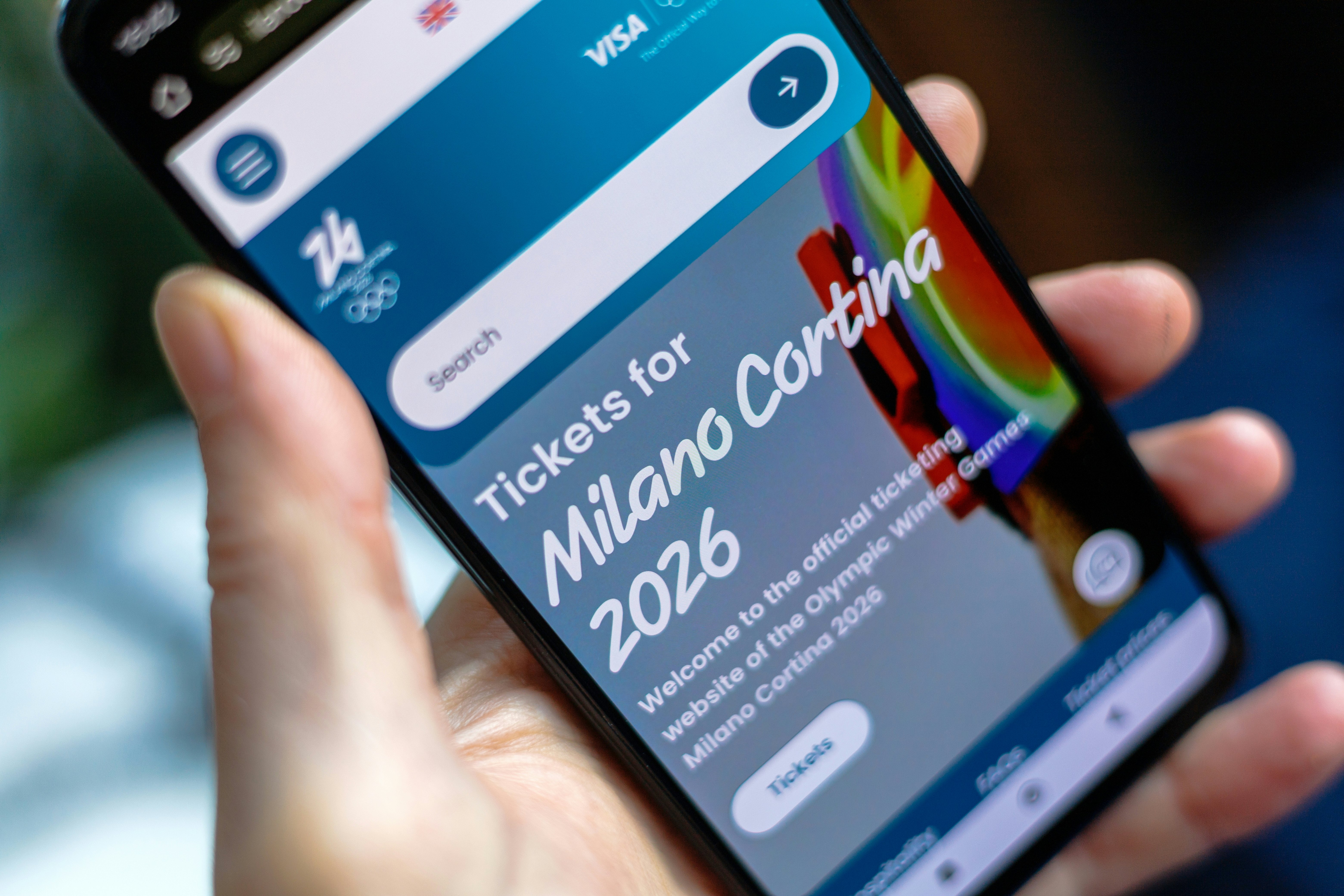 A person holds a smartphone displaying a website for buying sports tickets.