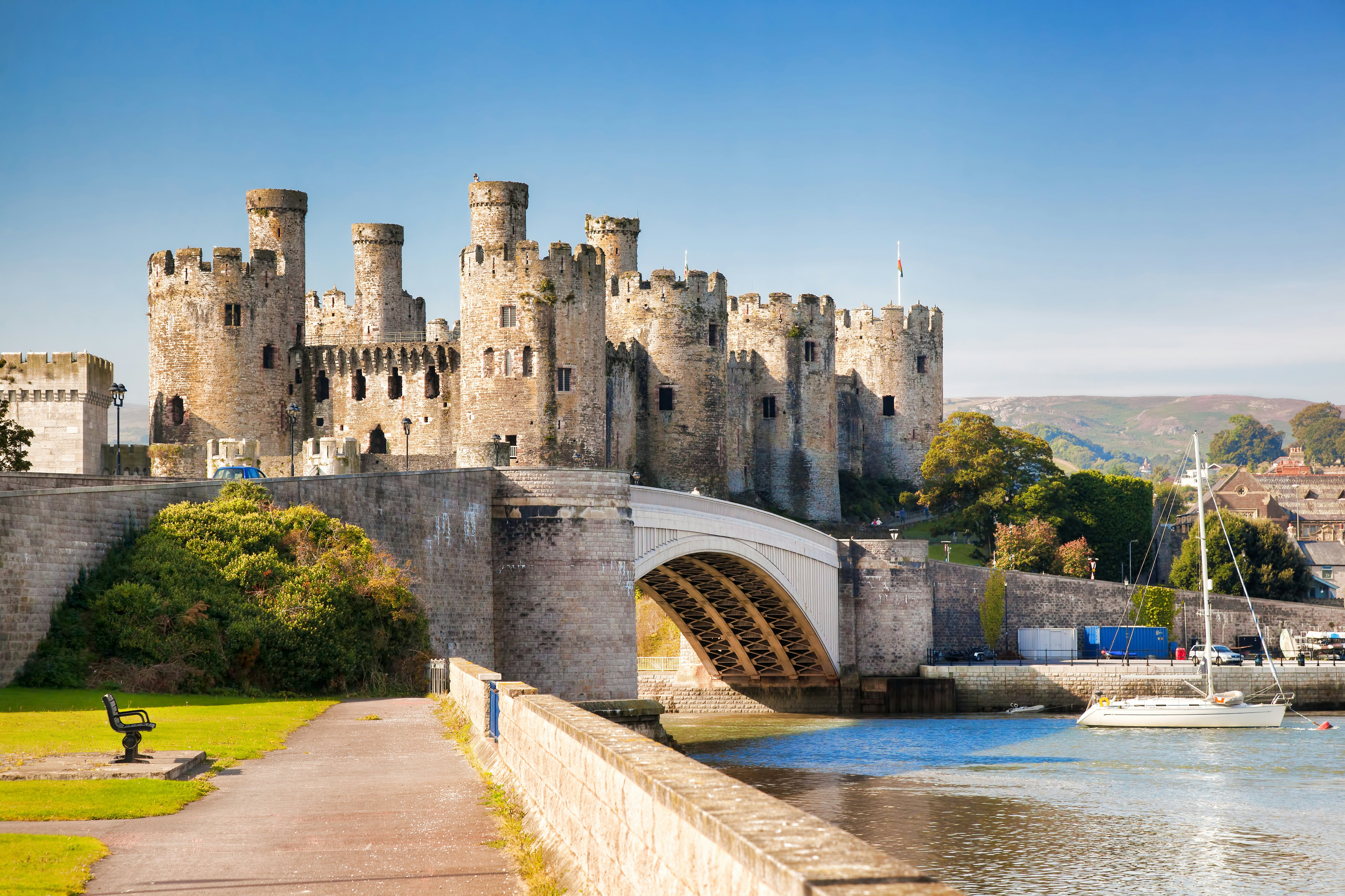 A view of Conwy Castle with a boat passing under the bridge, in Wales, UK.