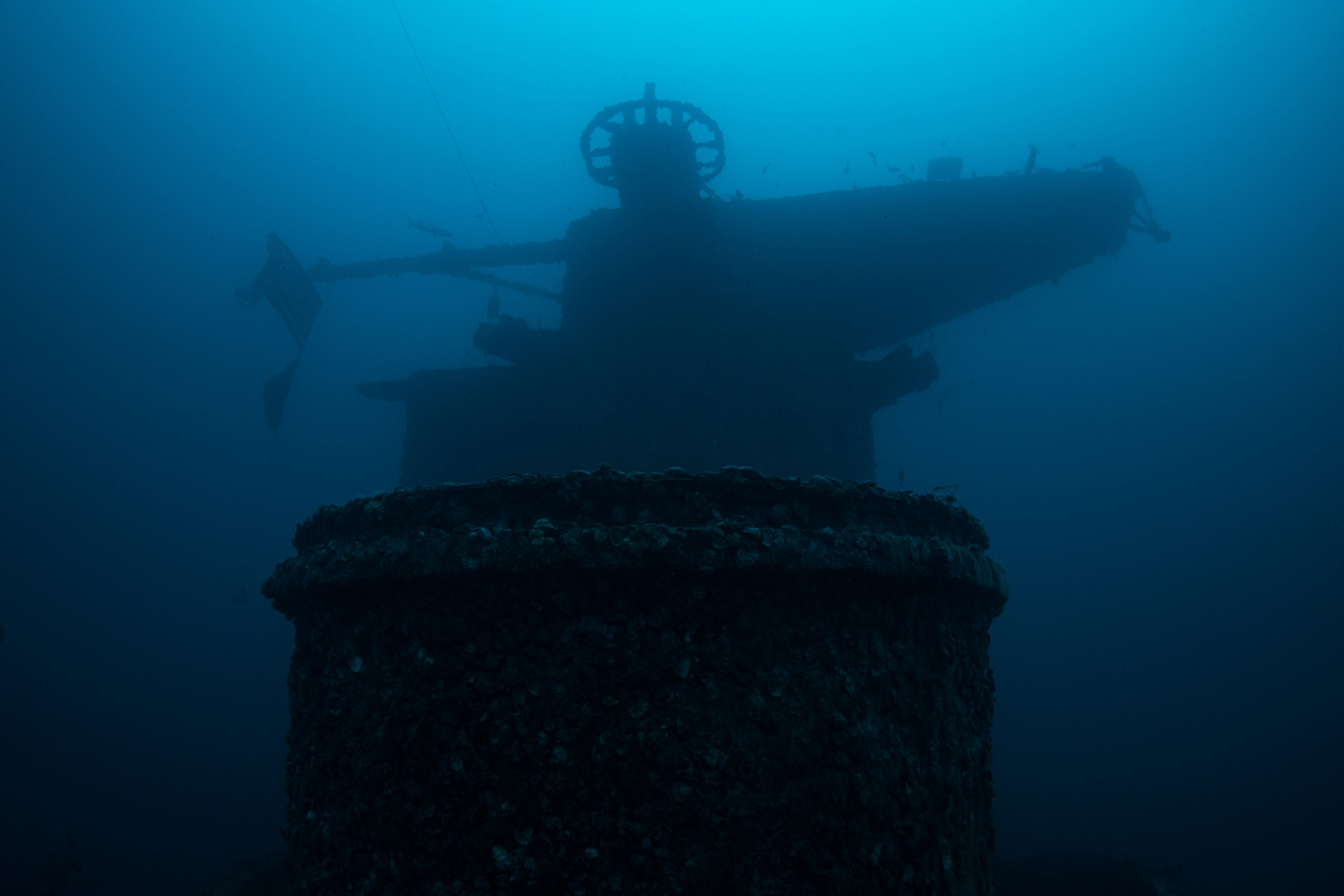 The bridge of a sunken warship is seen in murky underwater light.