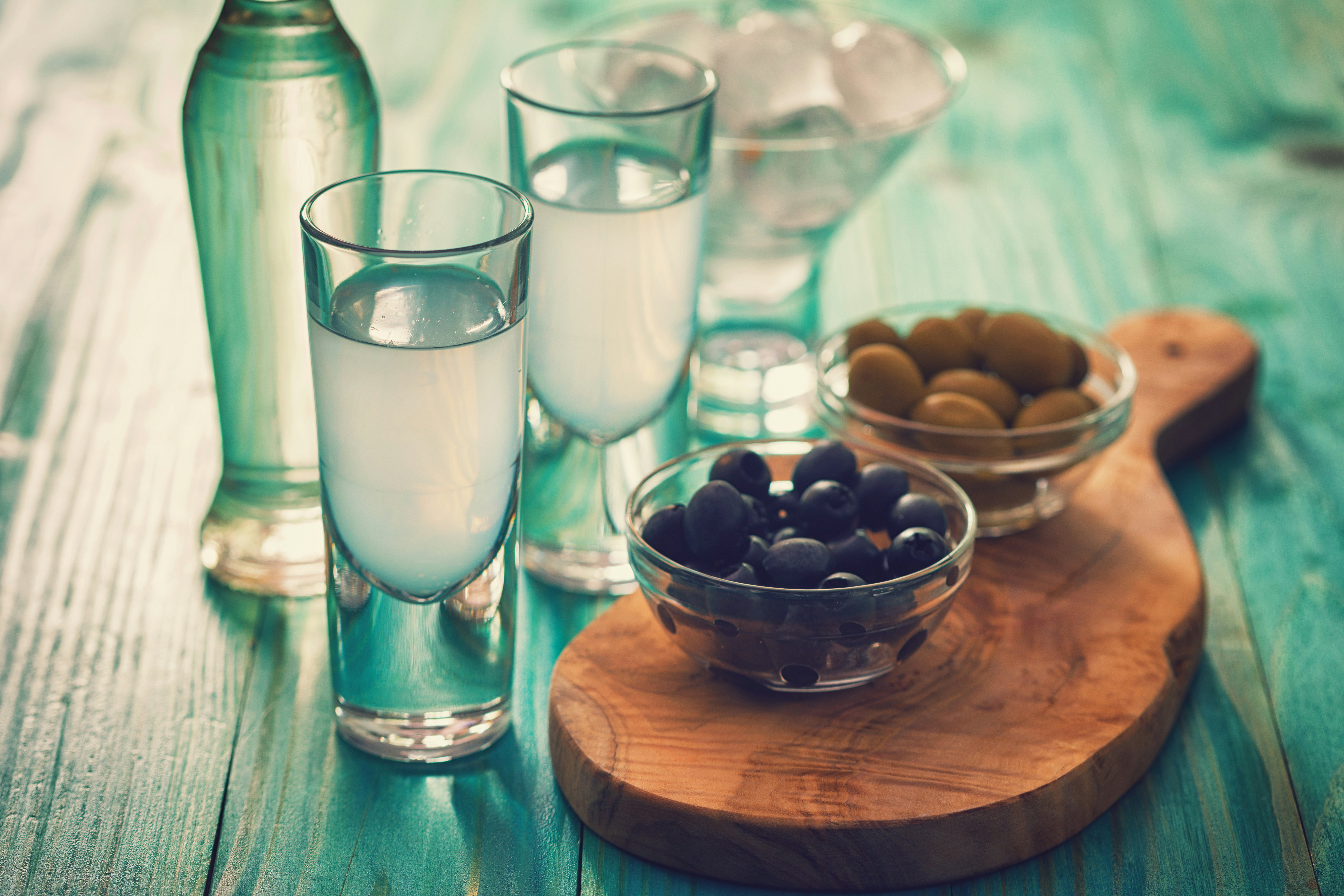 Chilled glasses of ouzo served with olives