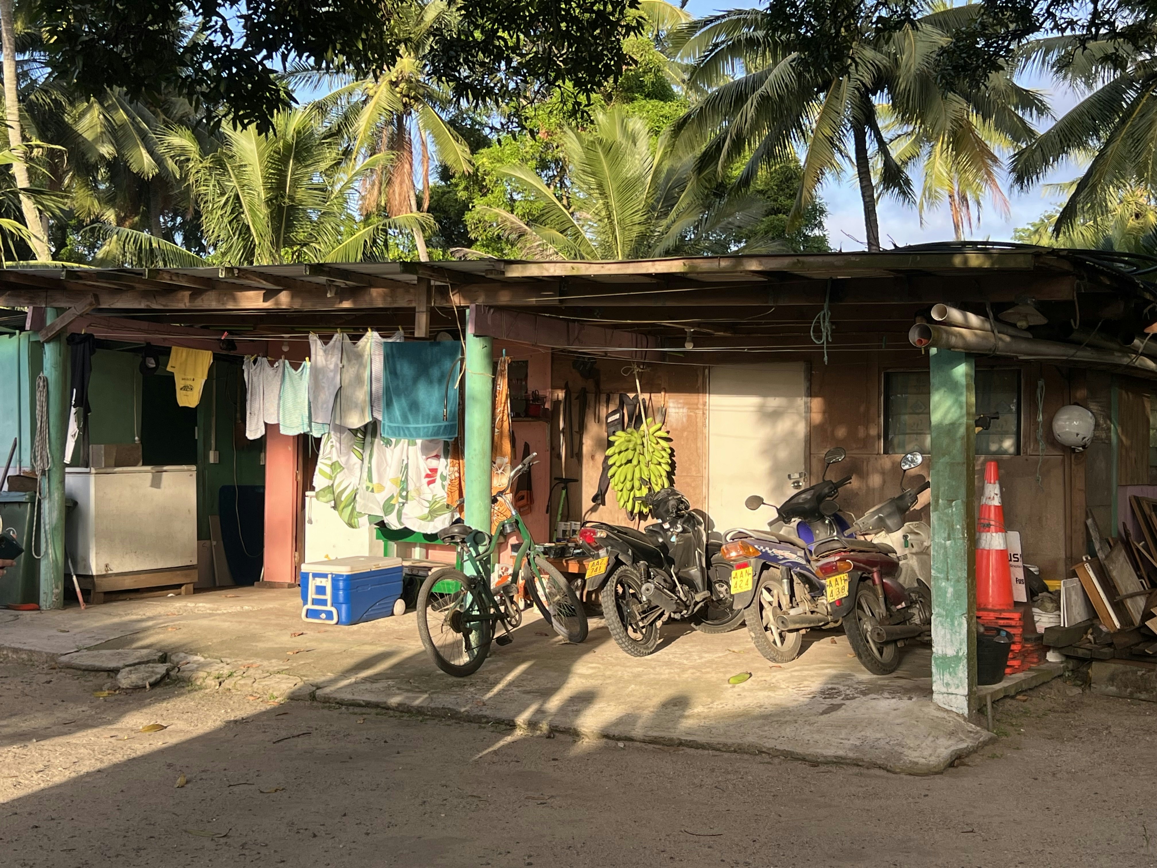 A low-rise building with a washing line, a bike and three motorcycles outside.