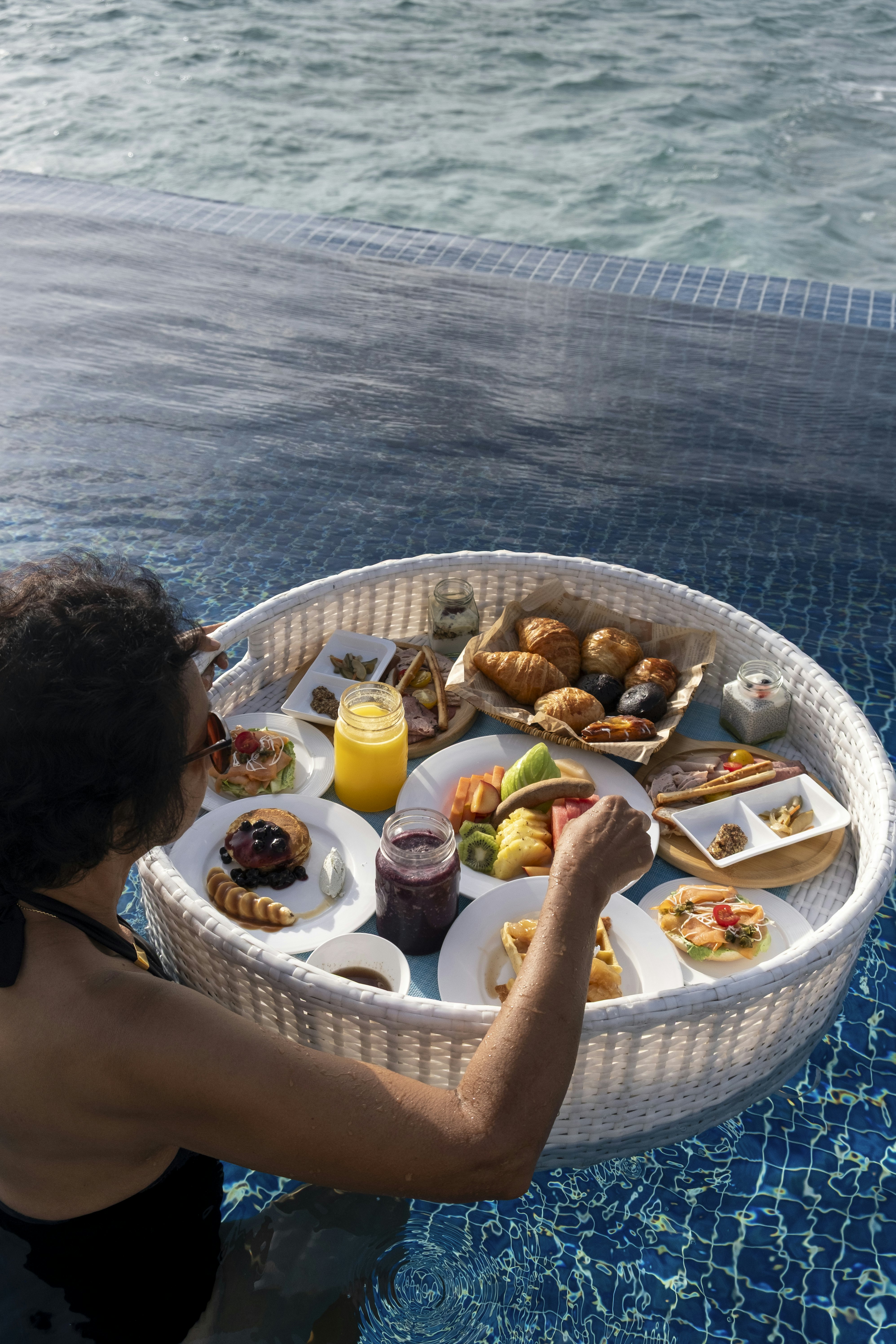 A woman digging into a floating breakfast at an overwater villa