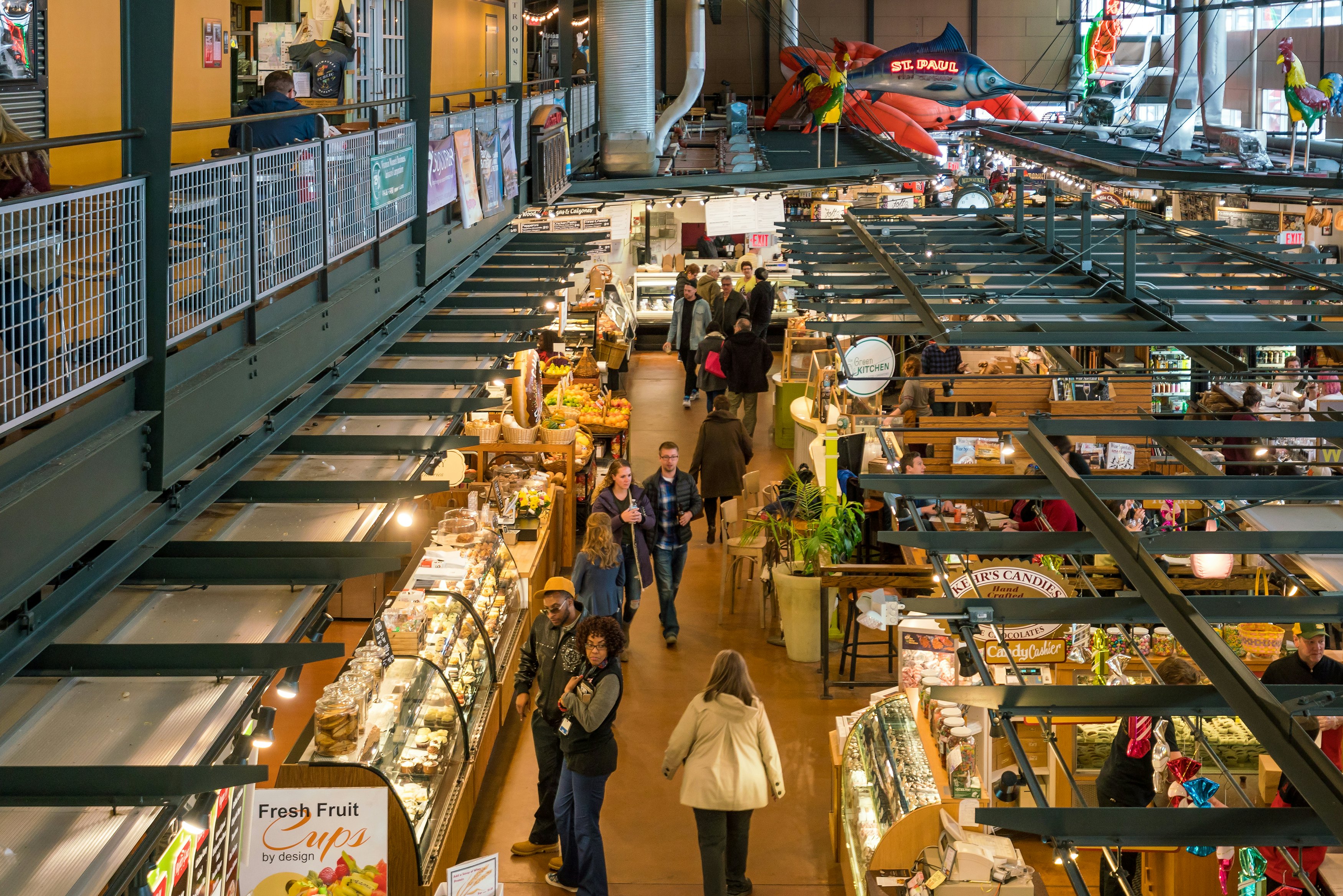People shopping at an indoor market with many food stalls on two levels.