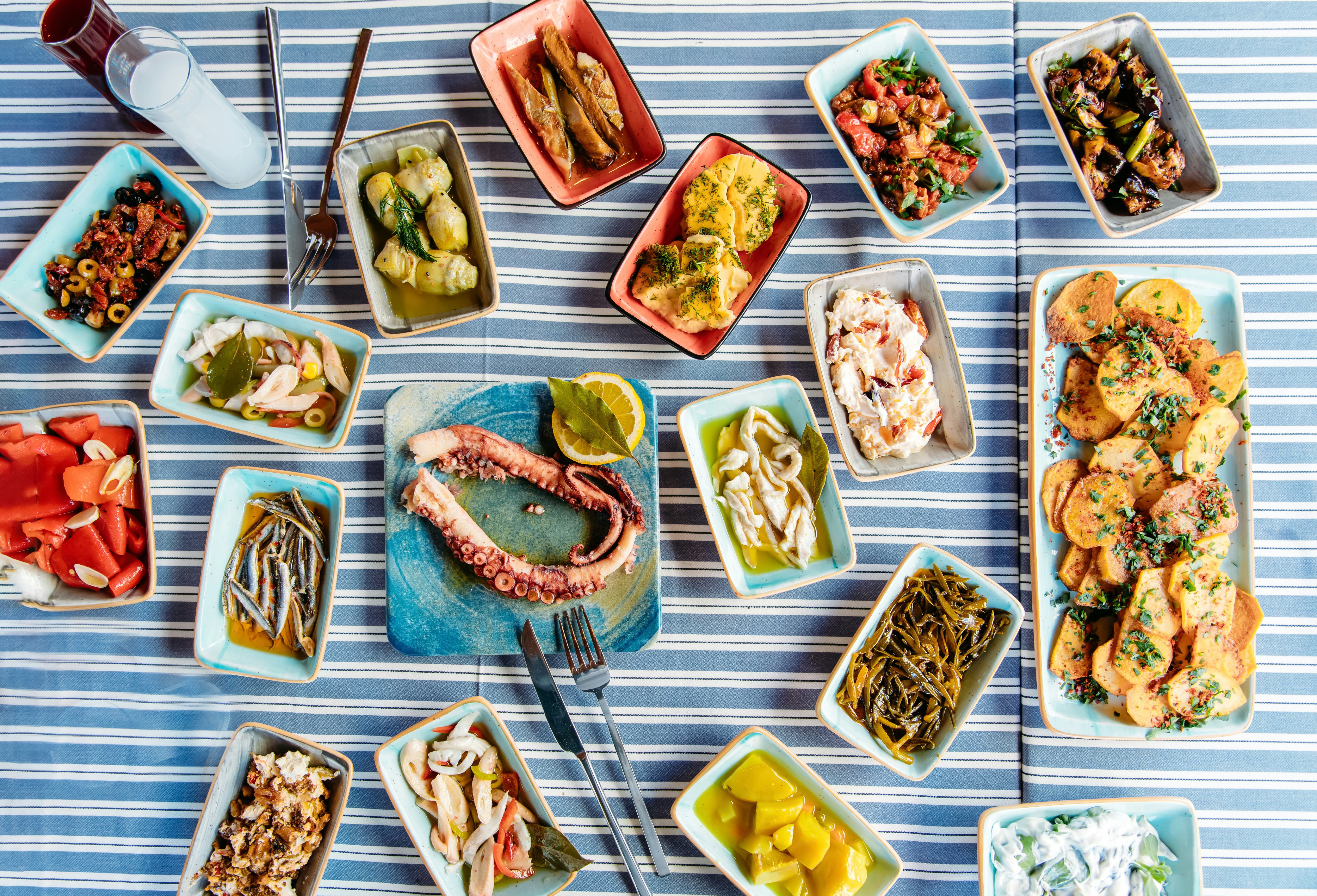Seafoods, grilled meat, meze, herbs, fish, raki, ouzo, appetizers and salads on the table for dinner or lunch at the beach from Greece