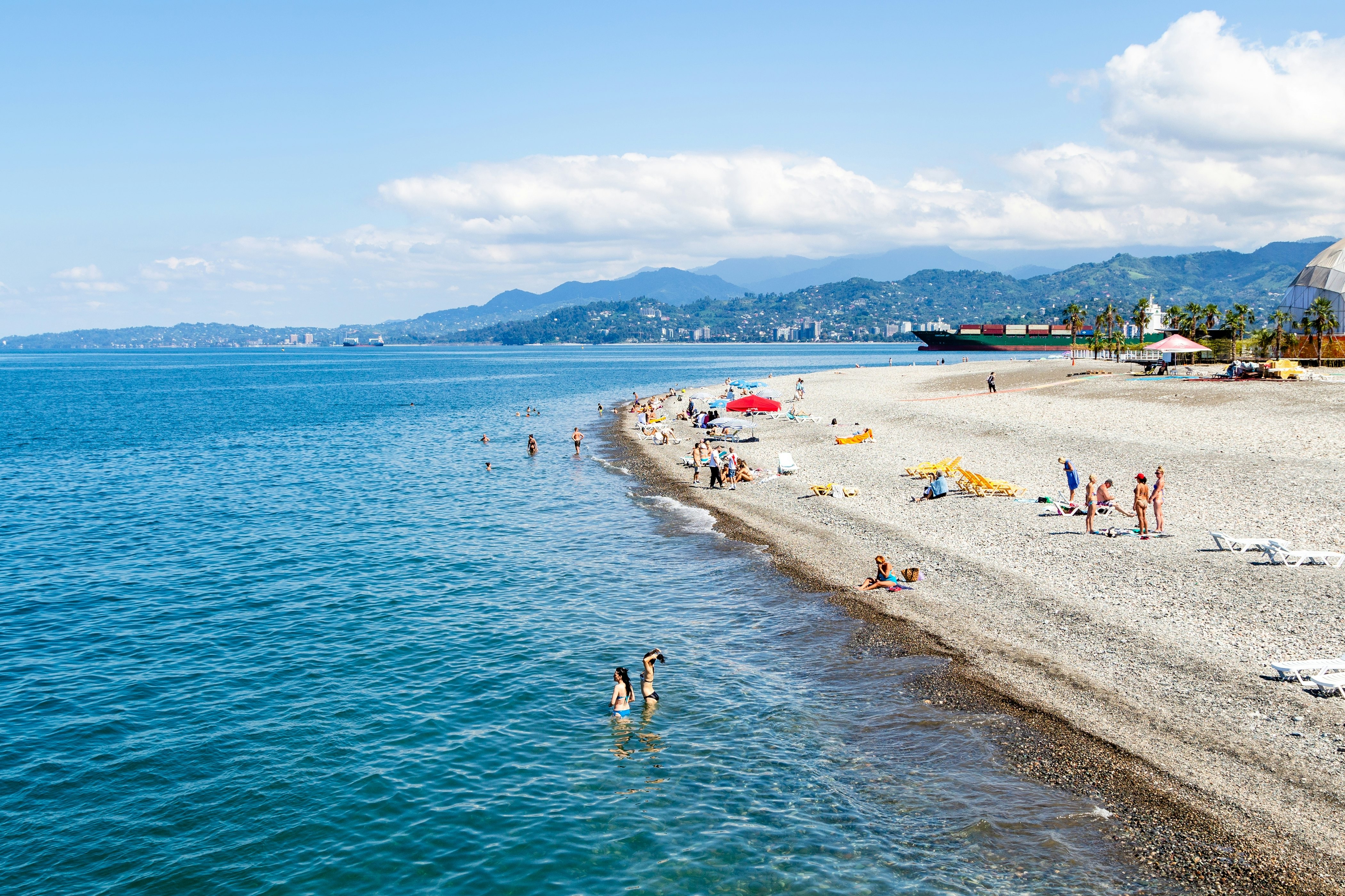 People relaxing on a pebble beach on a sunny day.