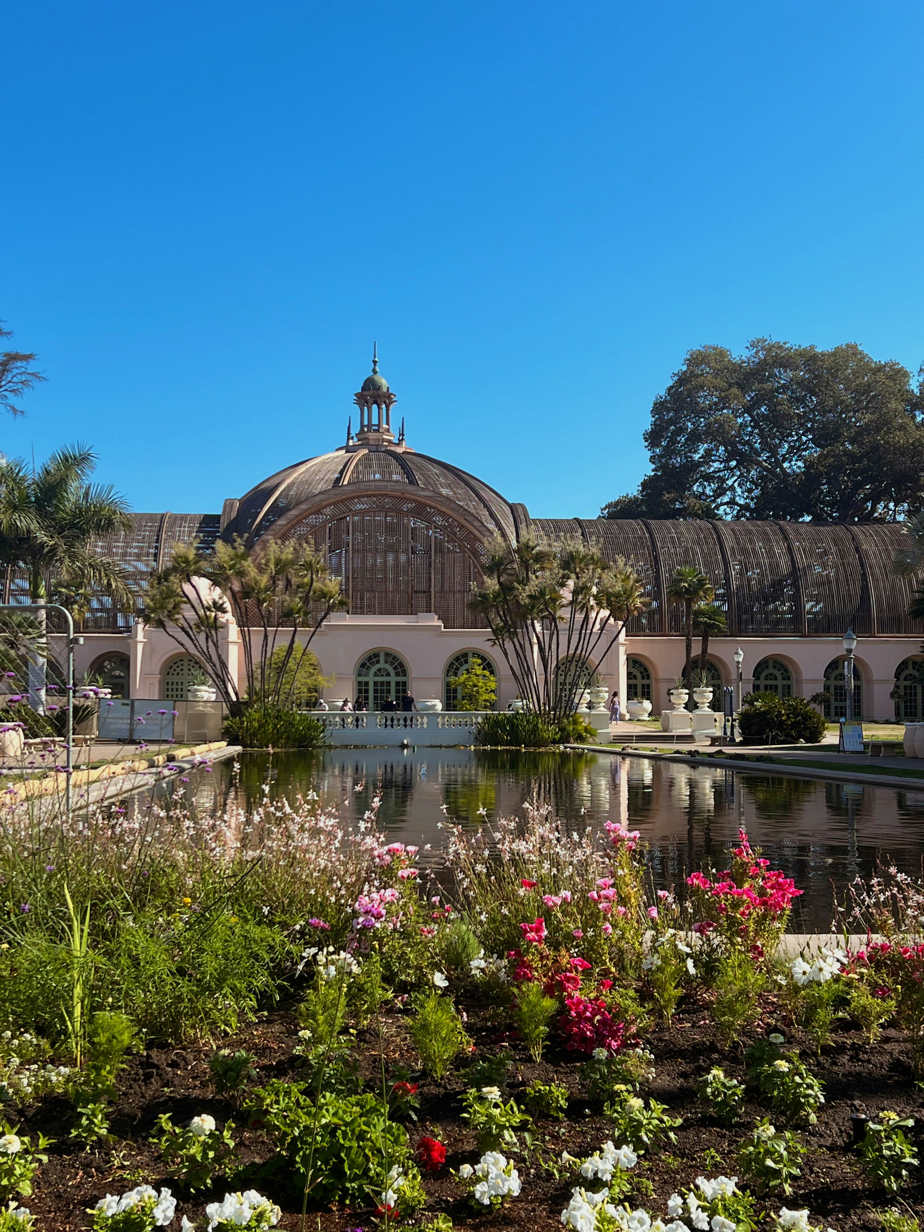 A botanical building with a rectangular pool in front on a sunny day.
