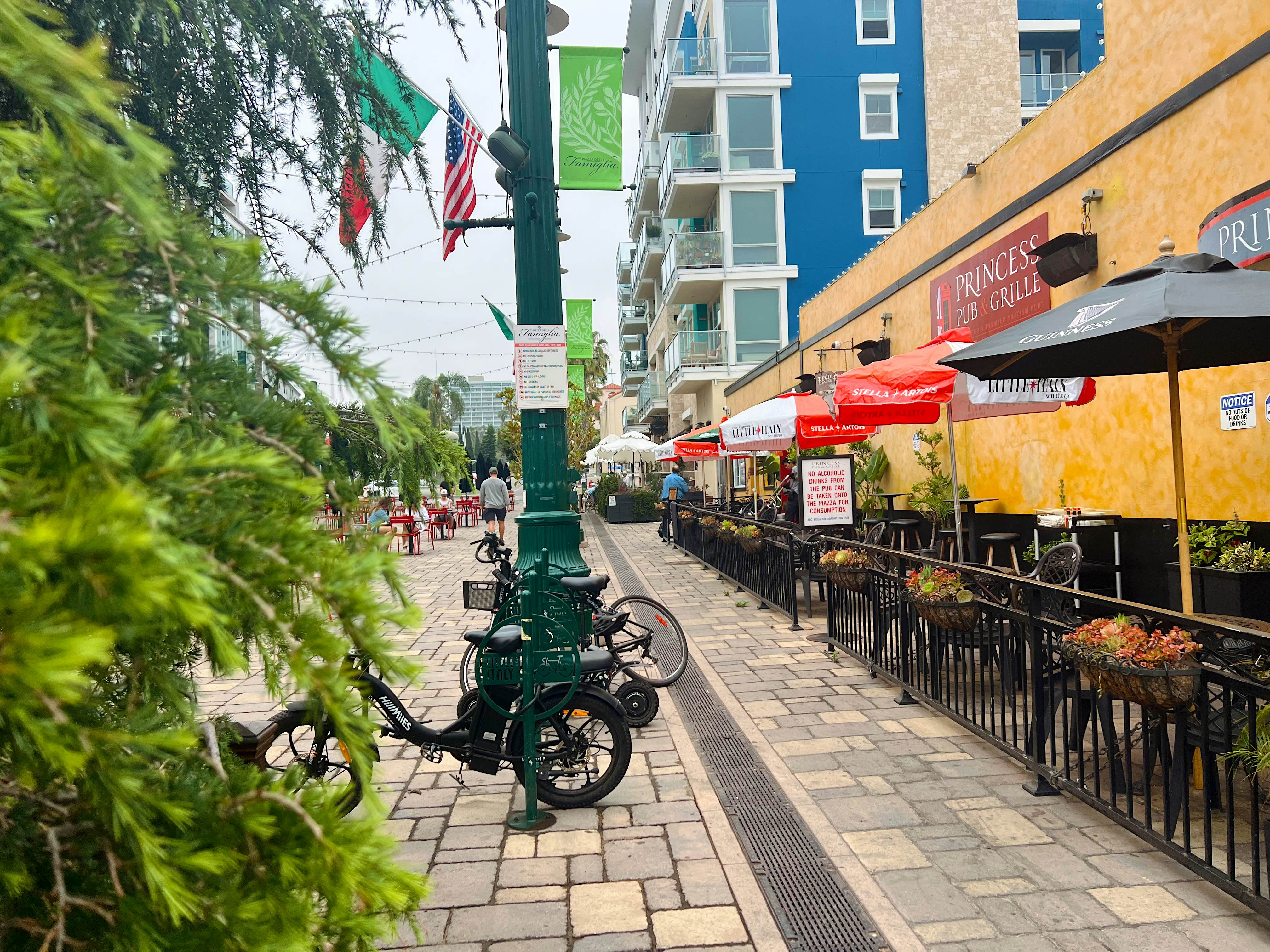 Streetscape with a café to the right and people walking in the distance on an overcast day.