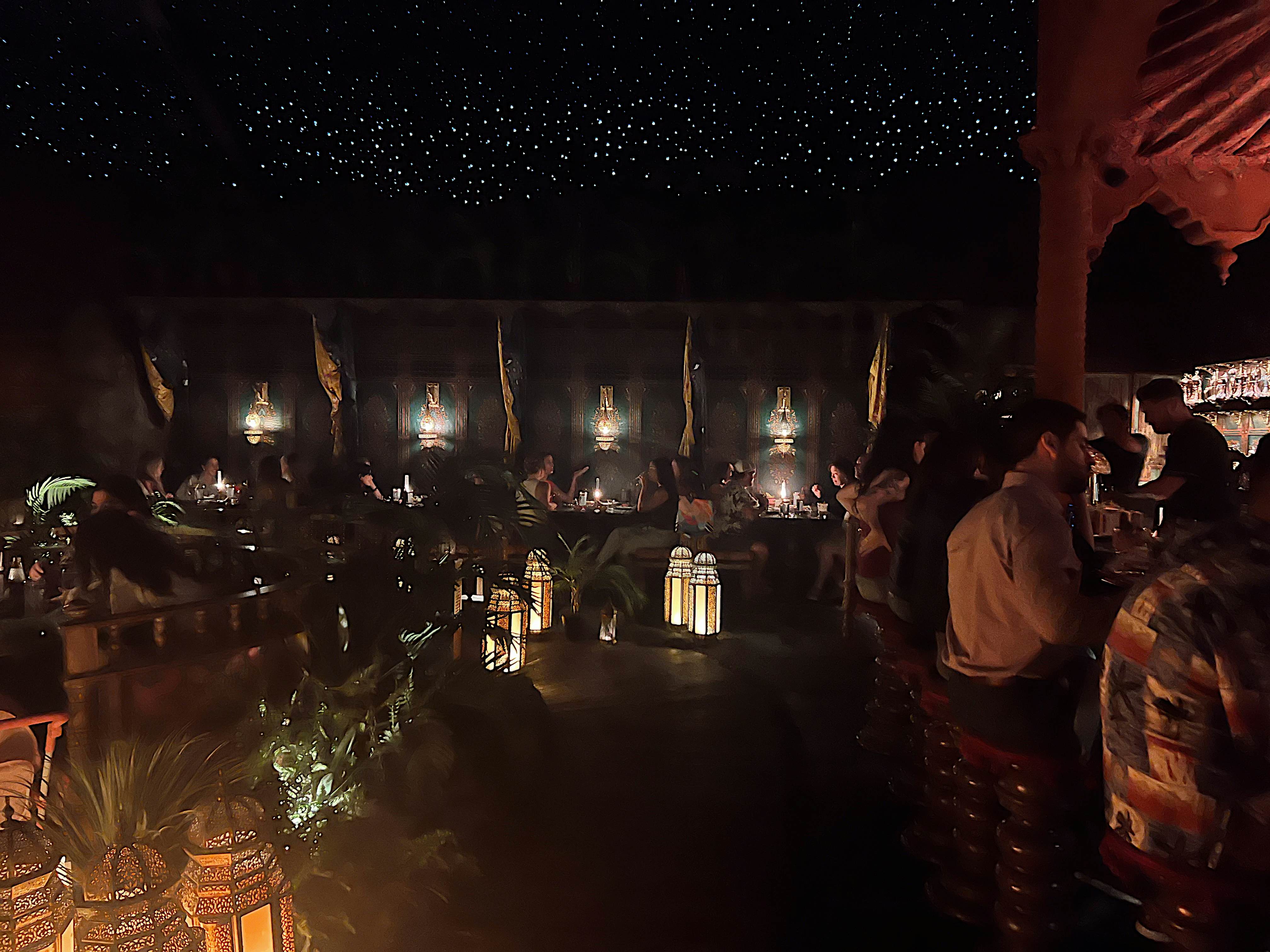 Diners inside a dark room with dramatic lighting placed throughout.