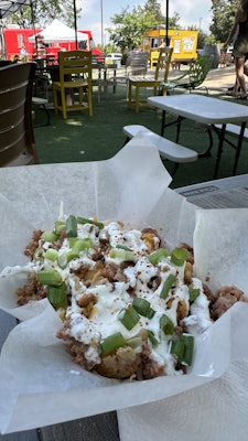 Sour cream and chives on top of a pile of tater tots.
