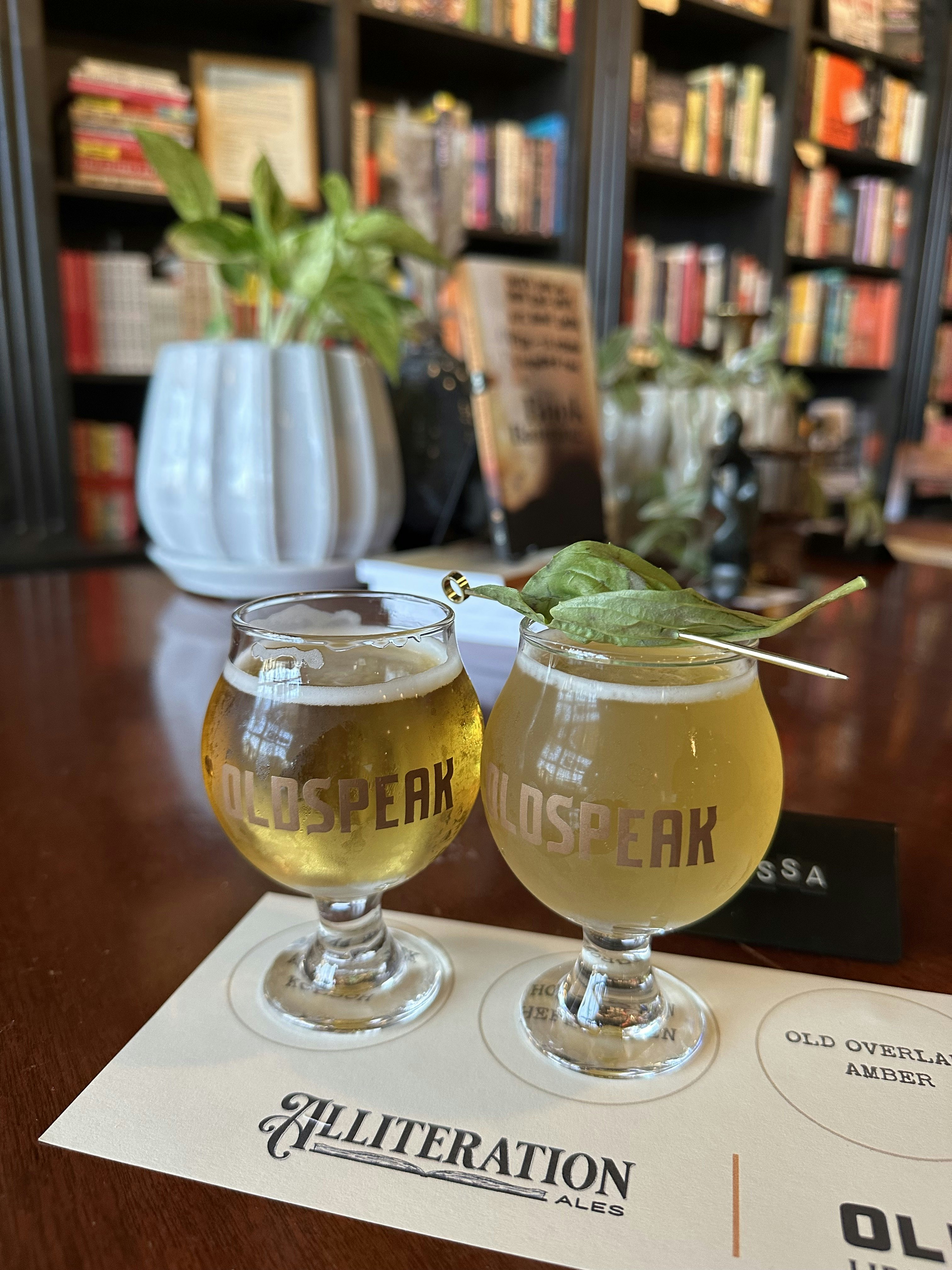 Two small glasses of beers in front of a bookcase