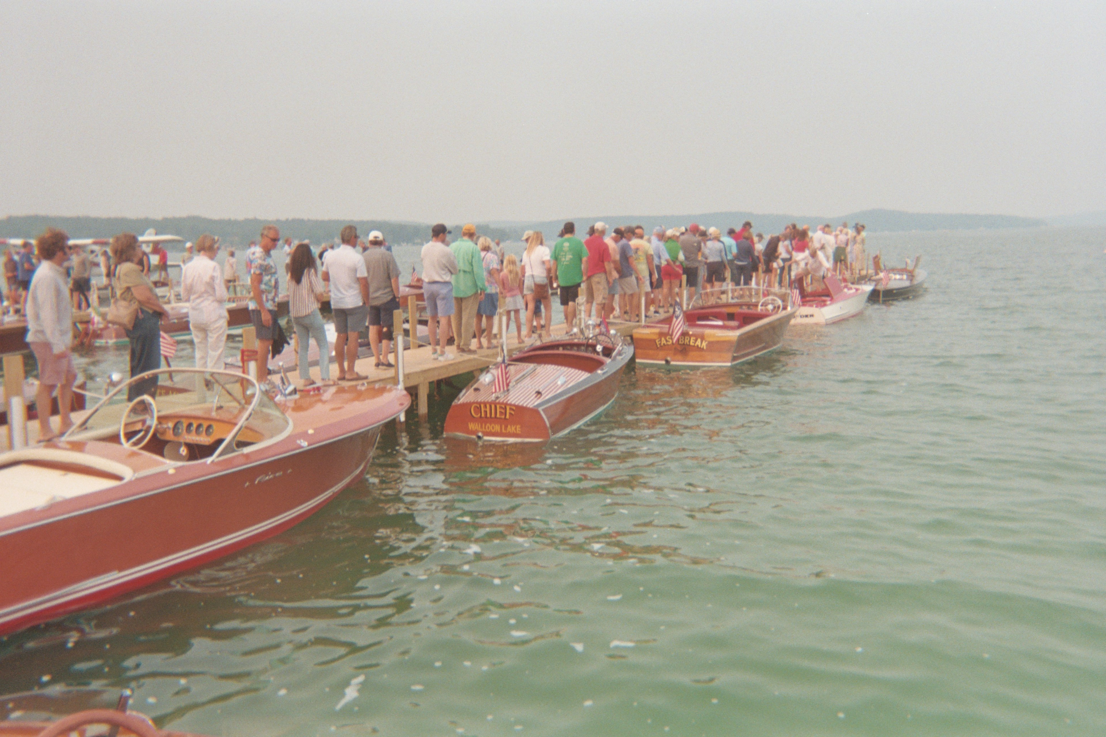 A group of people on a small dock observing boats