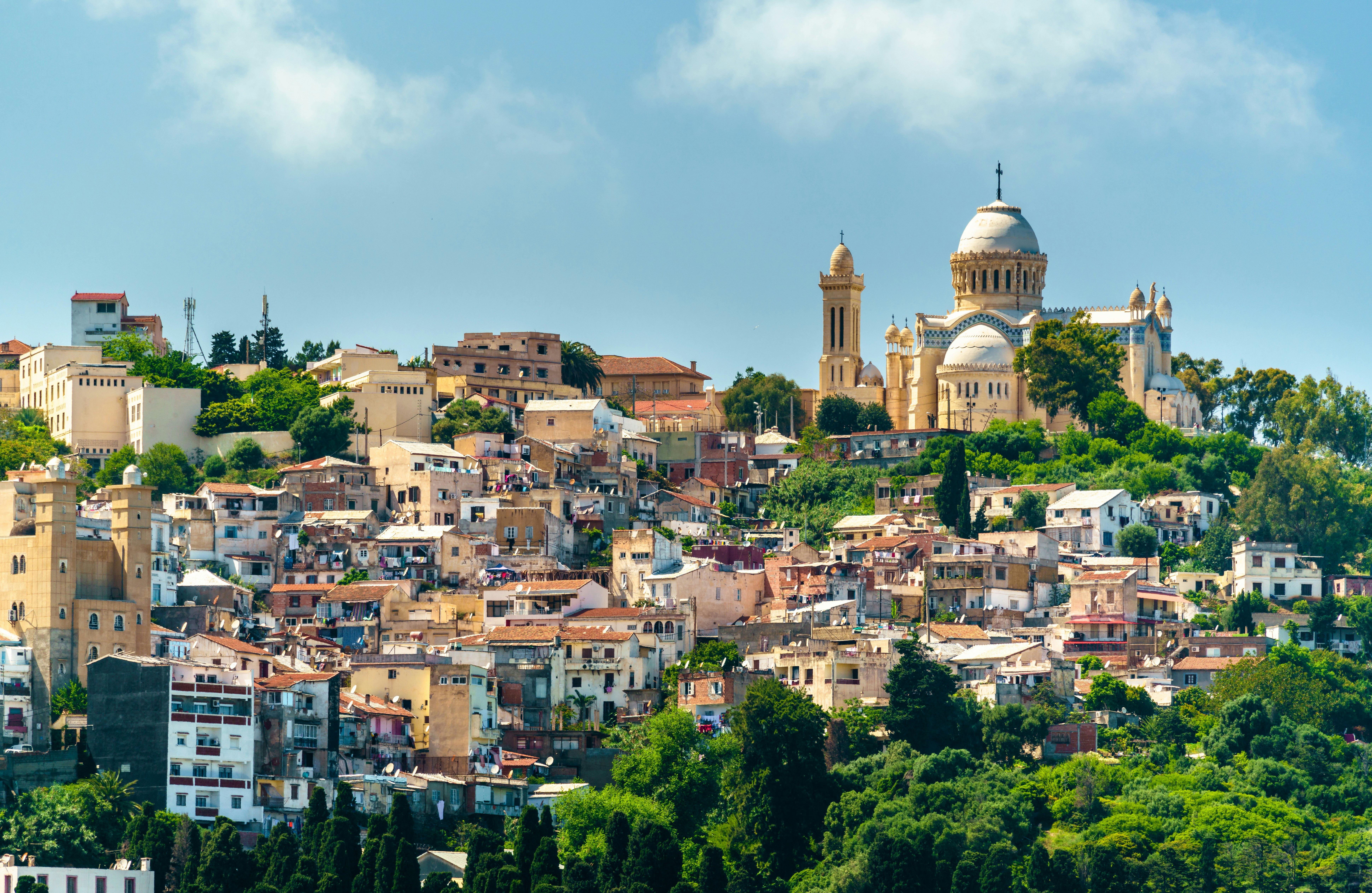 A dome-shaped church surrounded by a sloping hill covered with apartment buildings and trees.