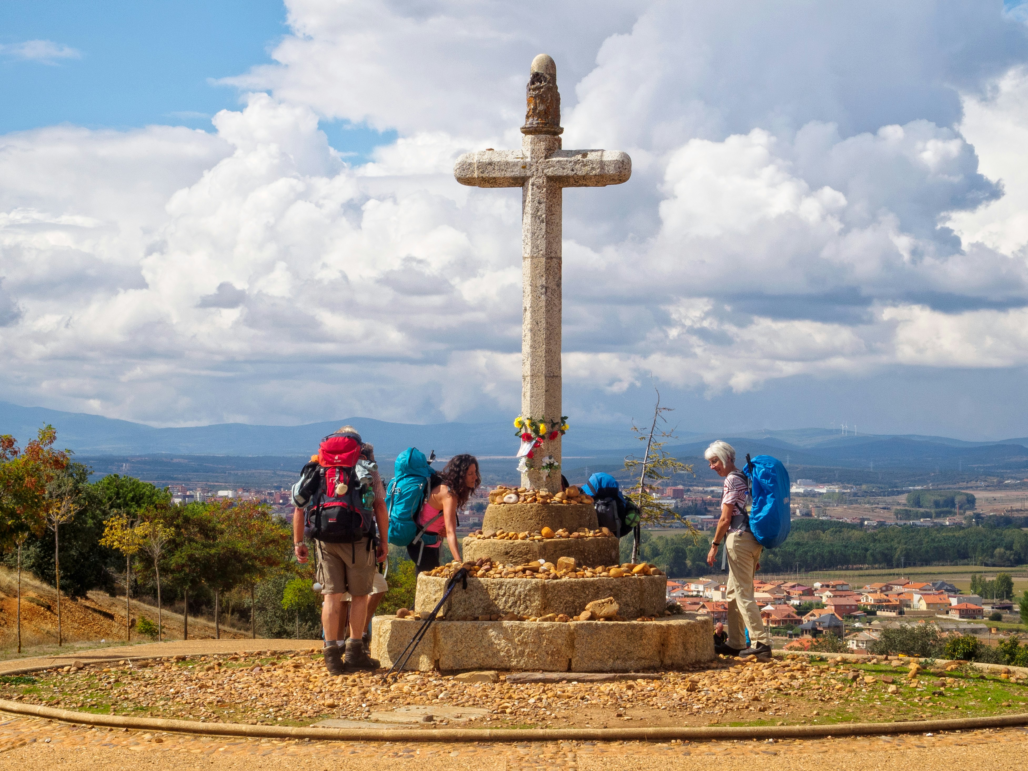 Pilgrims at the stone cross commemorating the 5th century Bishop Toribio, on the French route of the Camino de Santiago, Spain.