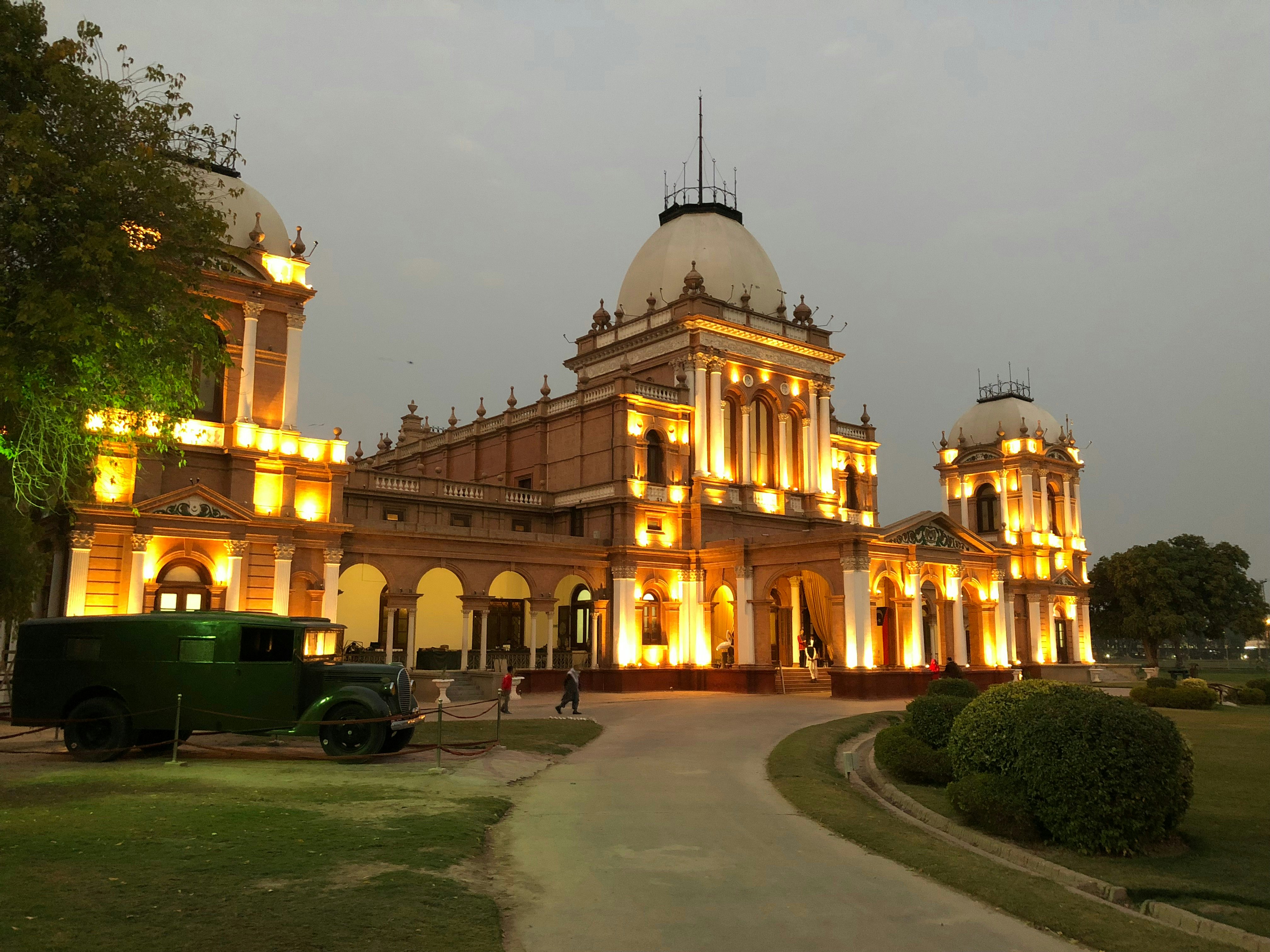 The exterior of a grand palace with a central low-lit dome at twilight.