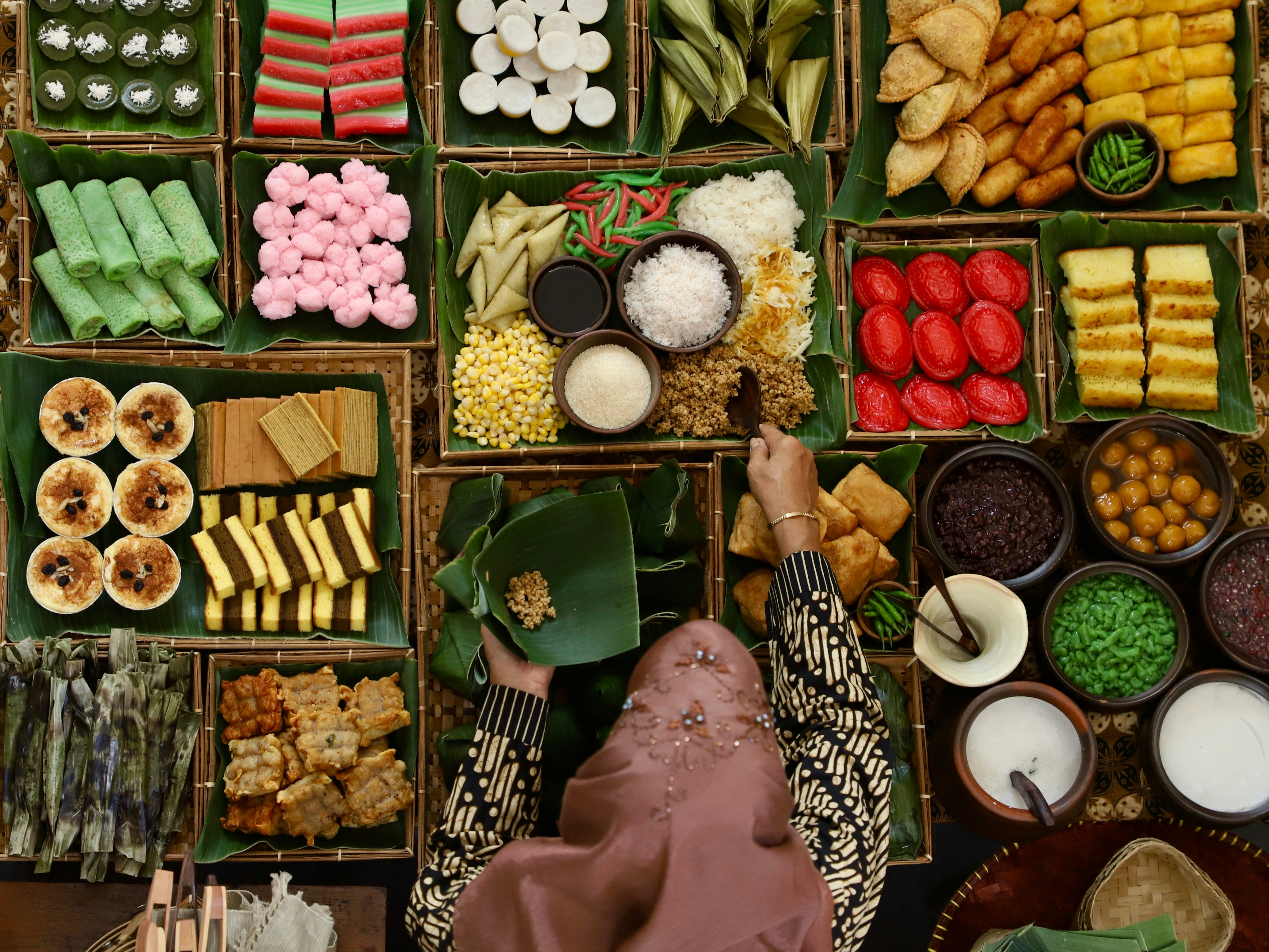 A food seller scooping tiwul at a market stall of Indonesian sweet and savory snacks