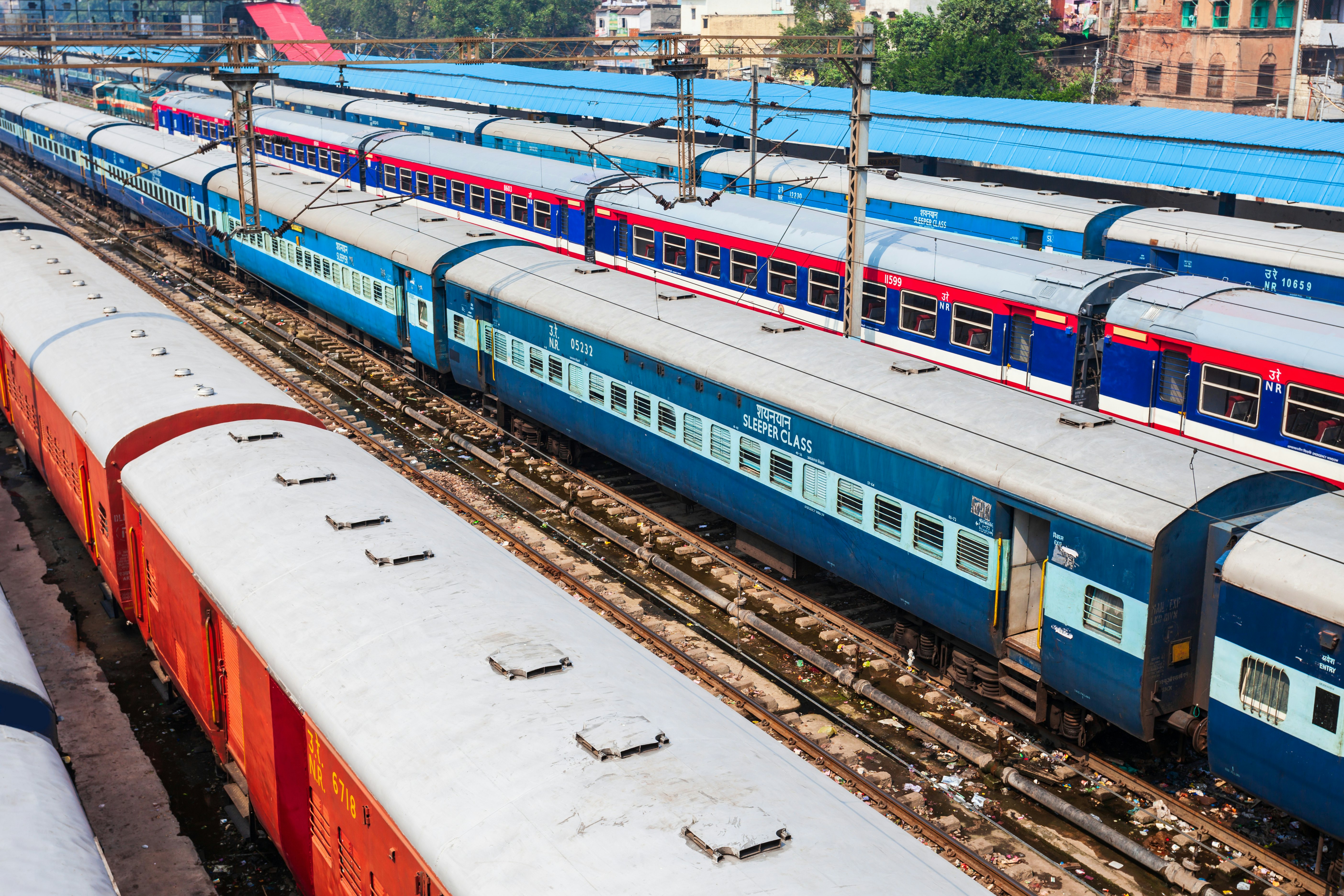 Coaches of four different trains standing in sidings at a major rail hub. One has "Sleeper Class" written on it in large letters.