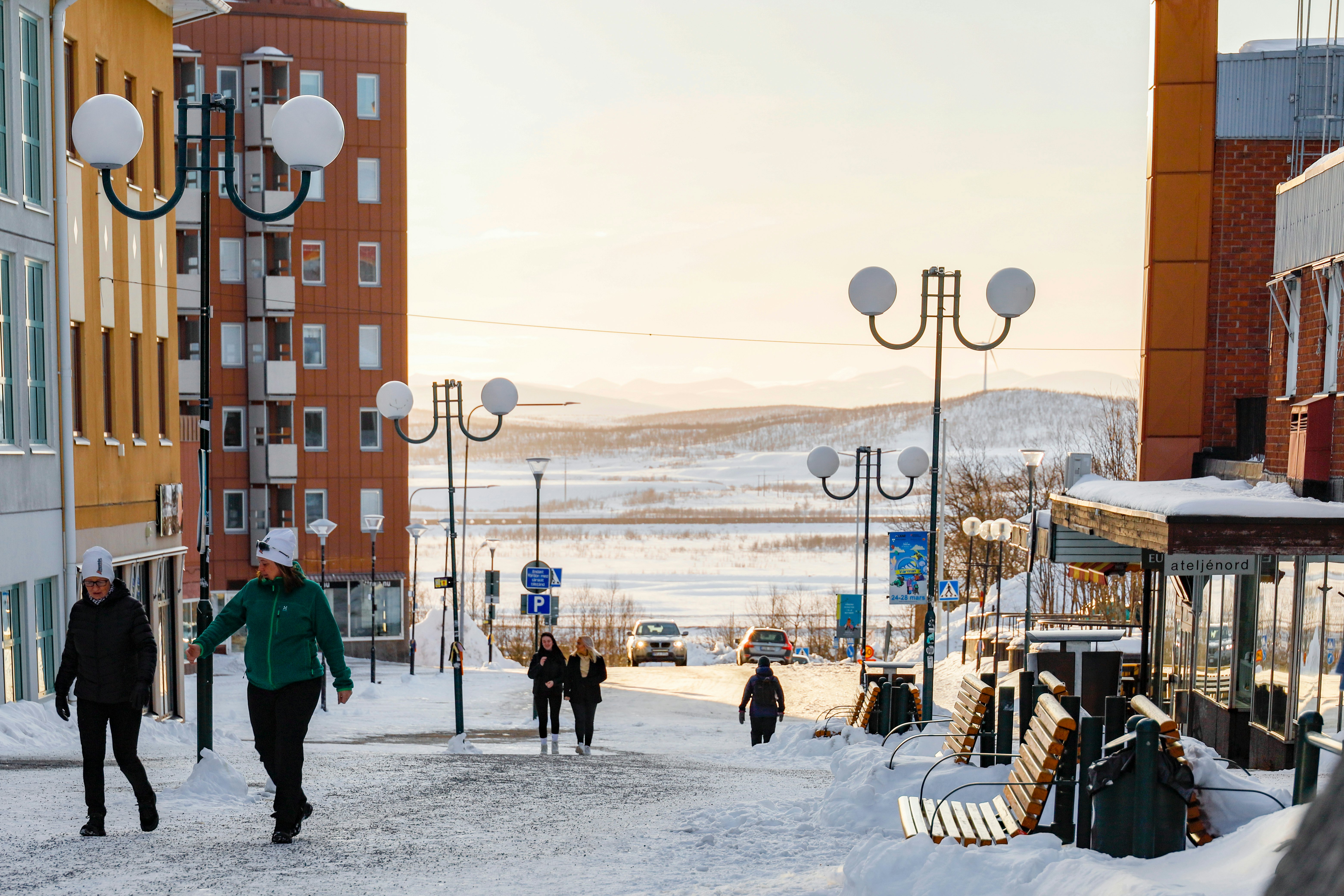 People walking on a snow-covered city street on a winter afternoon.