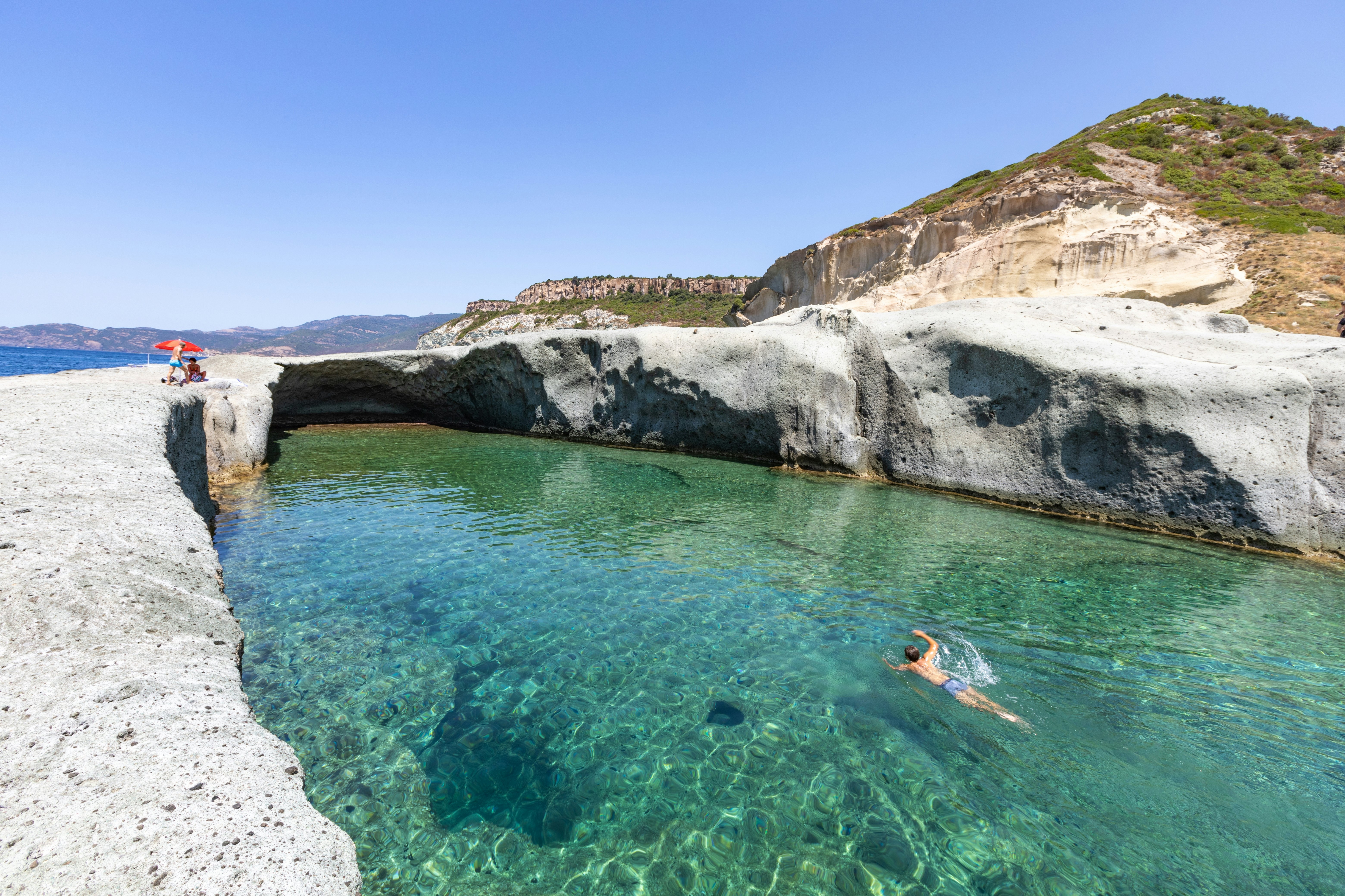 Cane Malu, a man swims in the beautiful natural pool carved into the rock on the west coast of Sardinia, Bosa, Oristano, Italy, Europe,