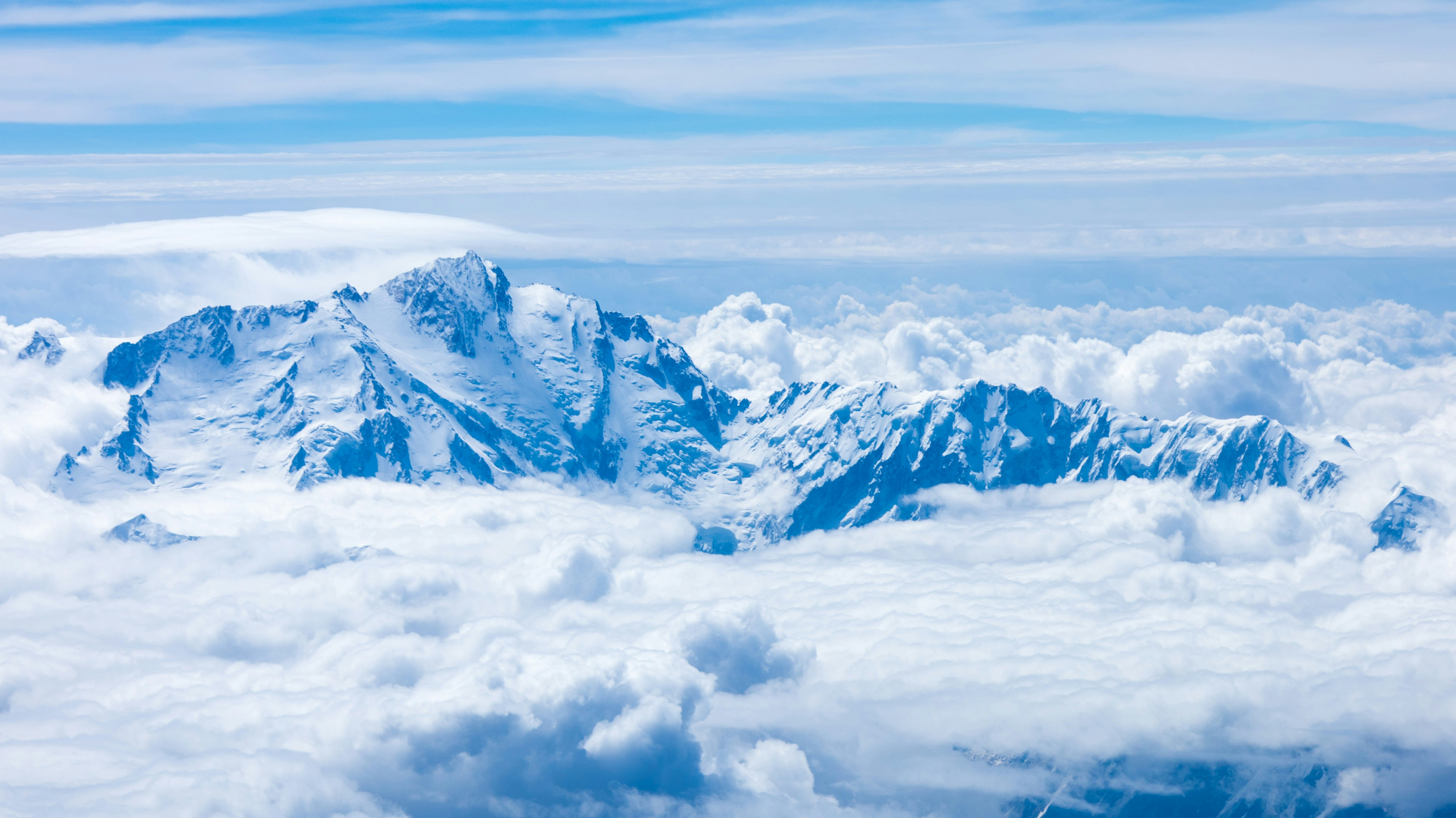 A vast snow-capped mountain range peaking above the clouds.