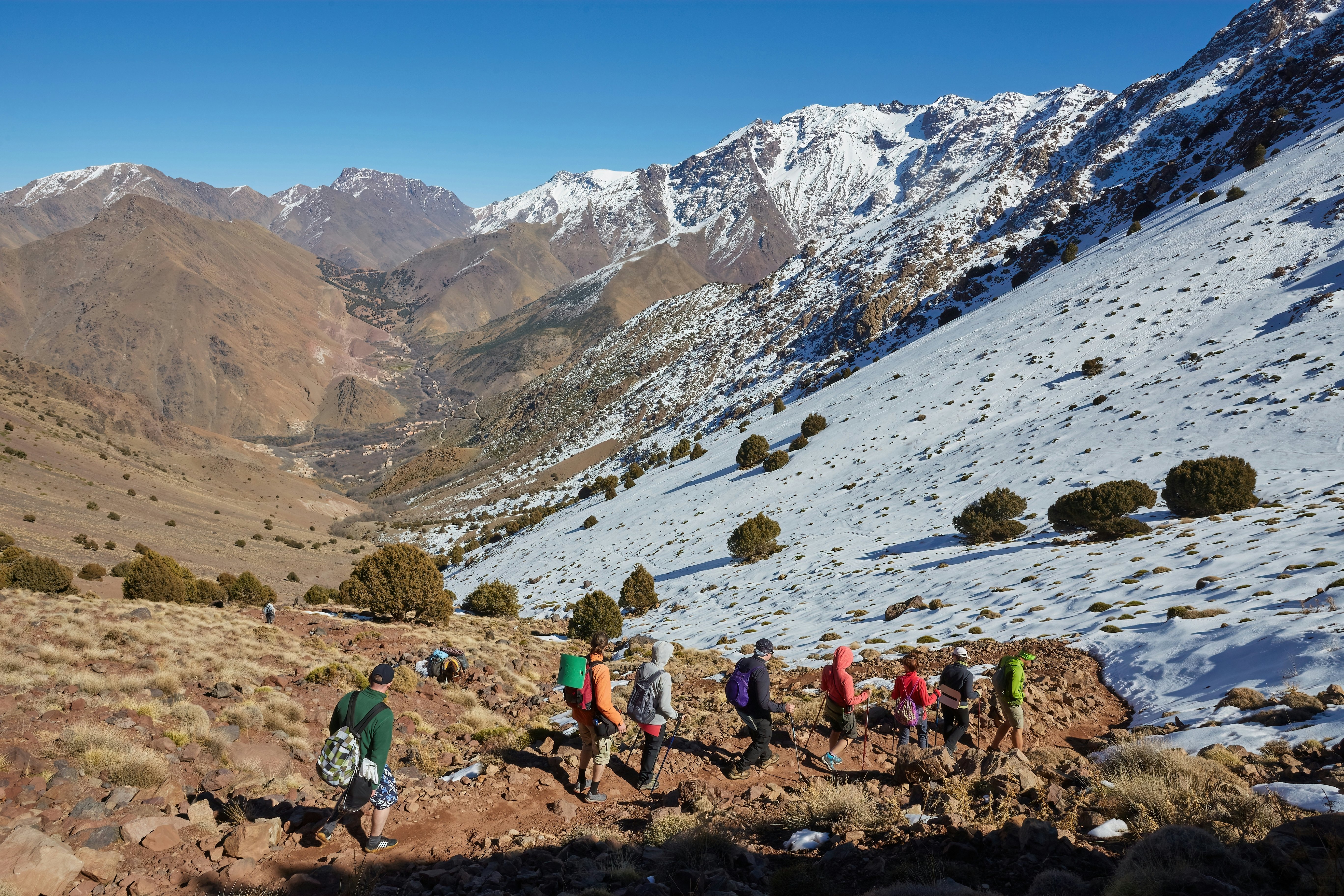 A group is hiking to the summit of Jebel Toubkal, highest mountain of Morocco. towards a snowy track.