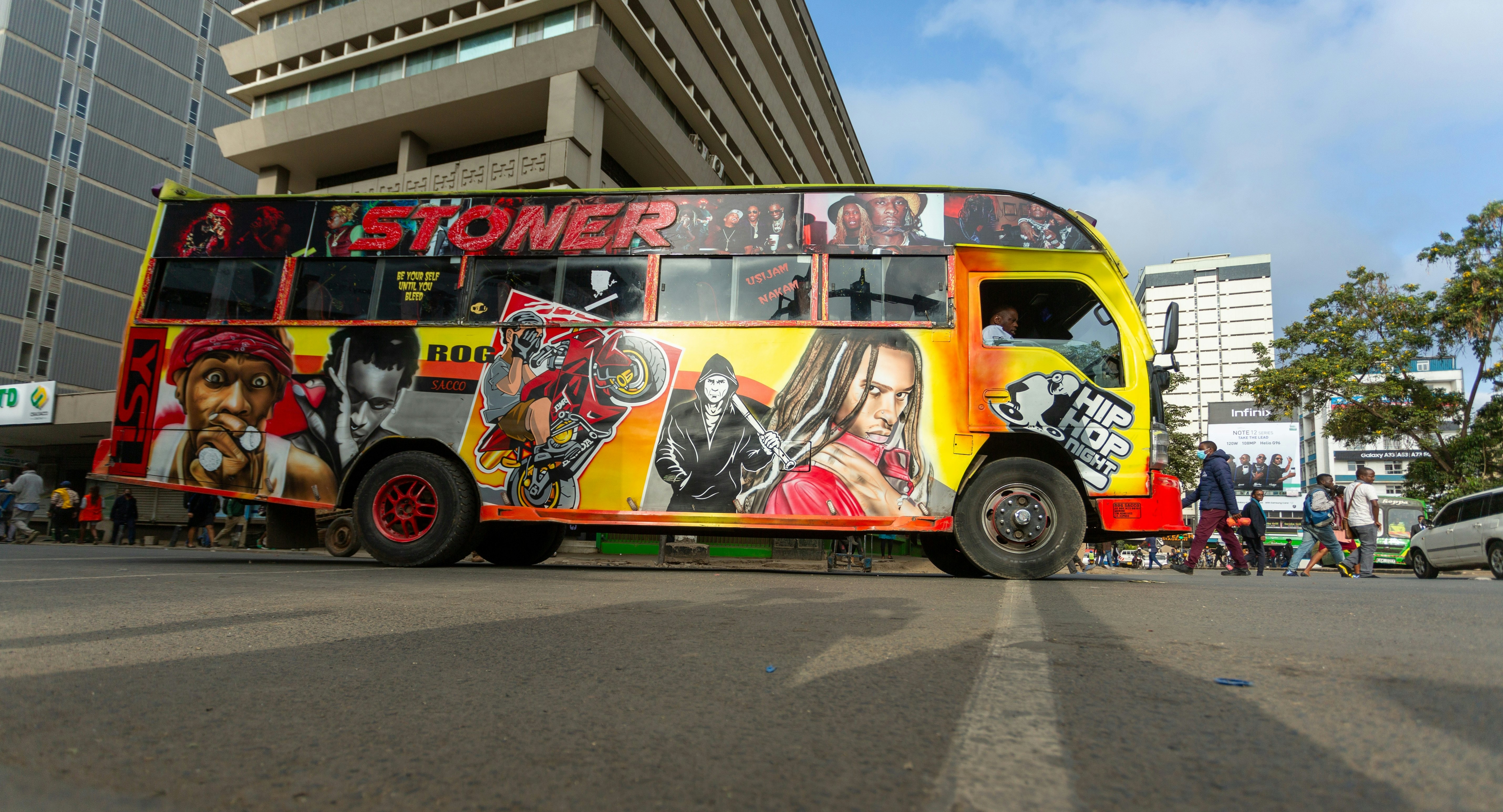 A bus painted with portraits of pop-culture figures hits the streets of a city.