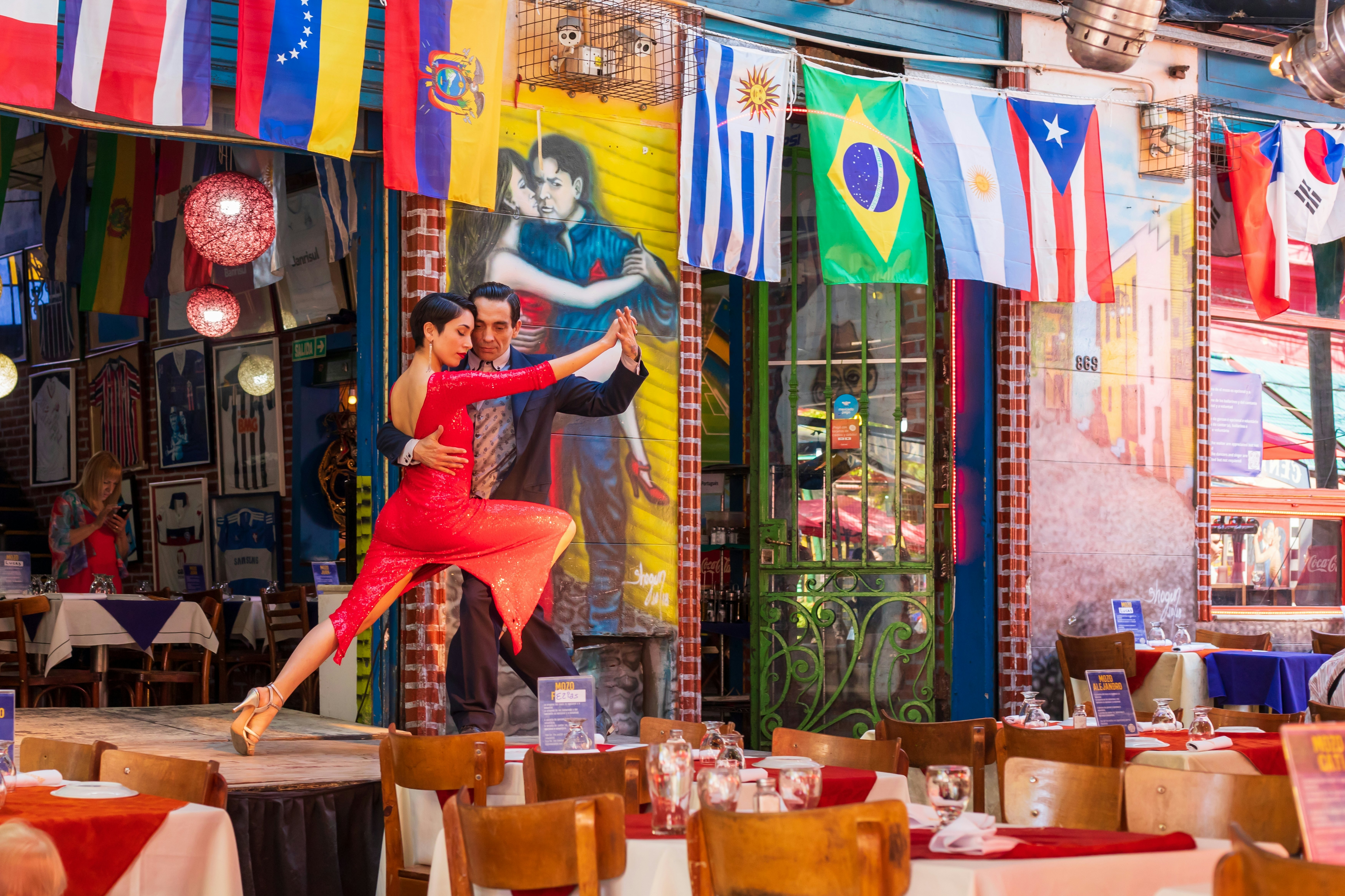 Two people tango on stage at a restaurant in Caminito