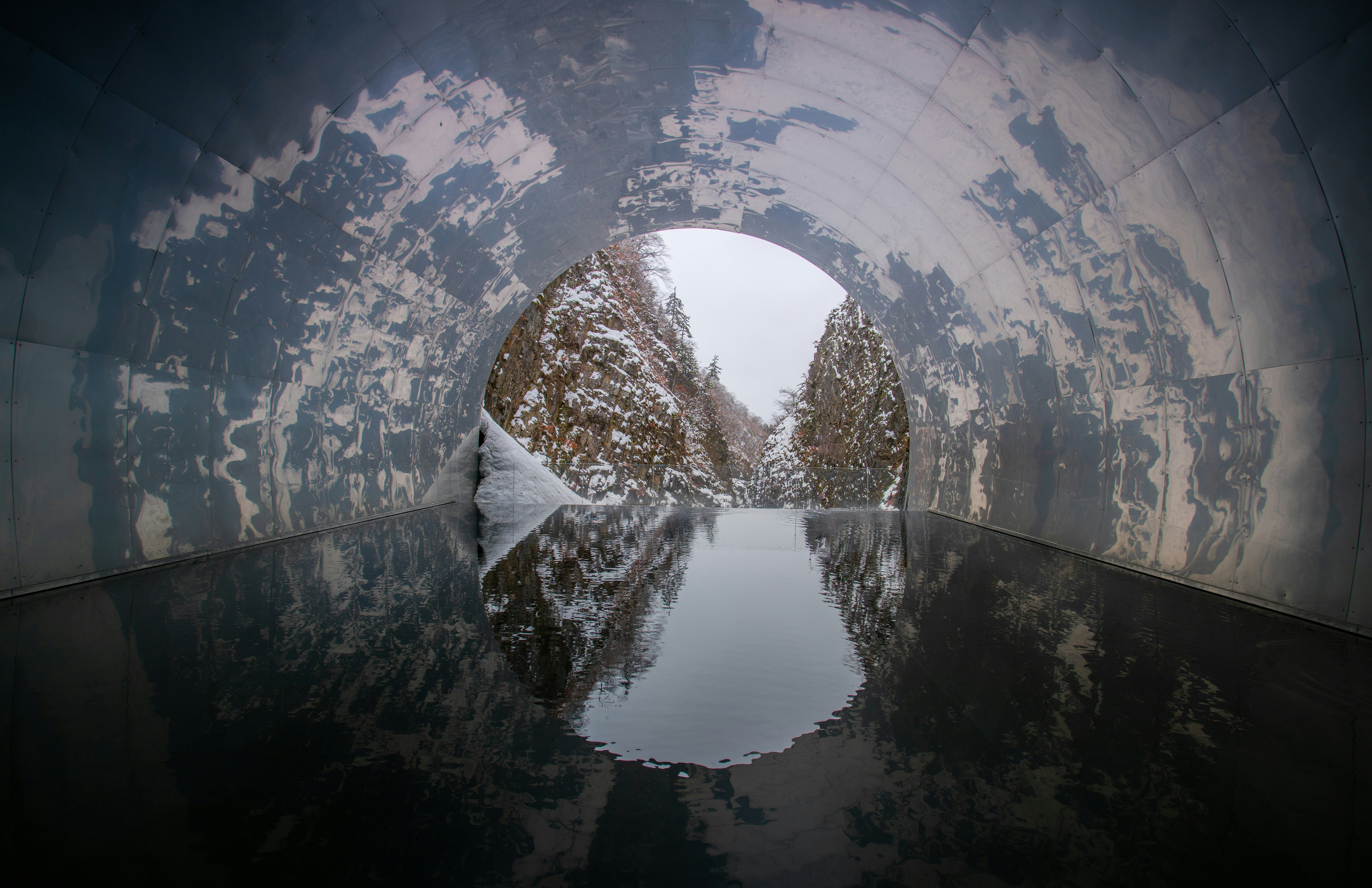 A snowy landscape in Japan is visible through a tunnel with an art installation.